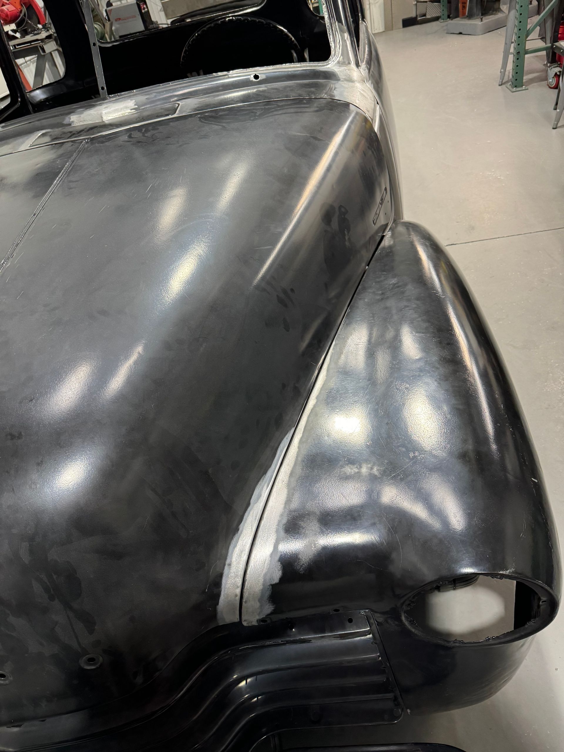 A close up of a black car hood in a garage.