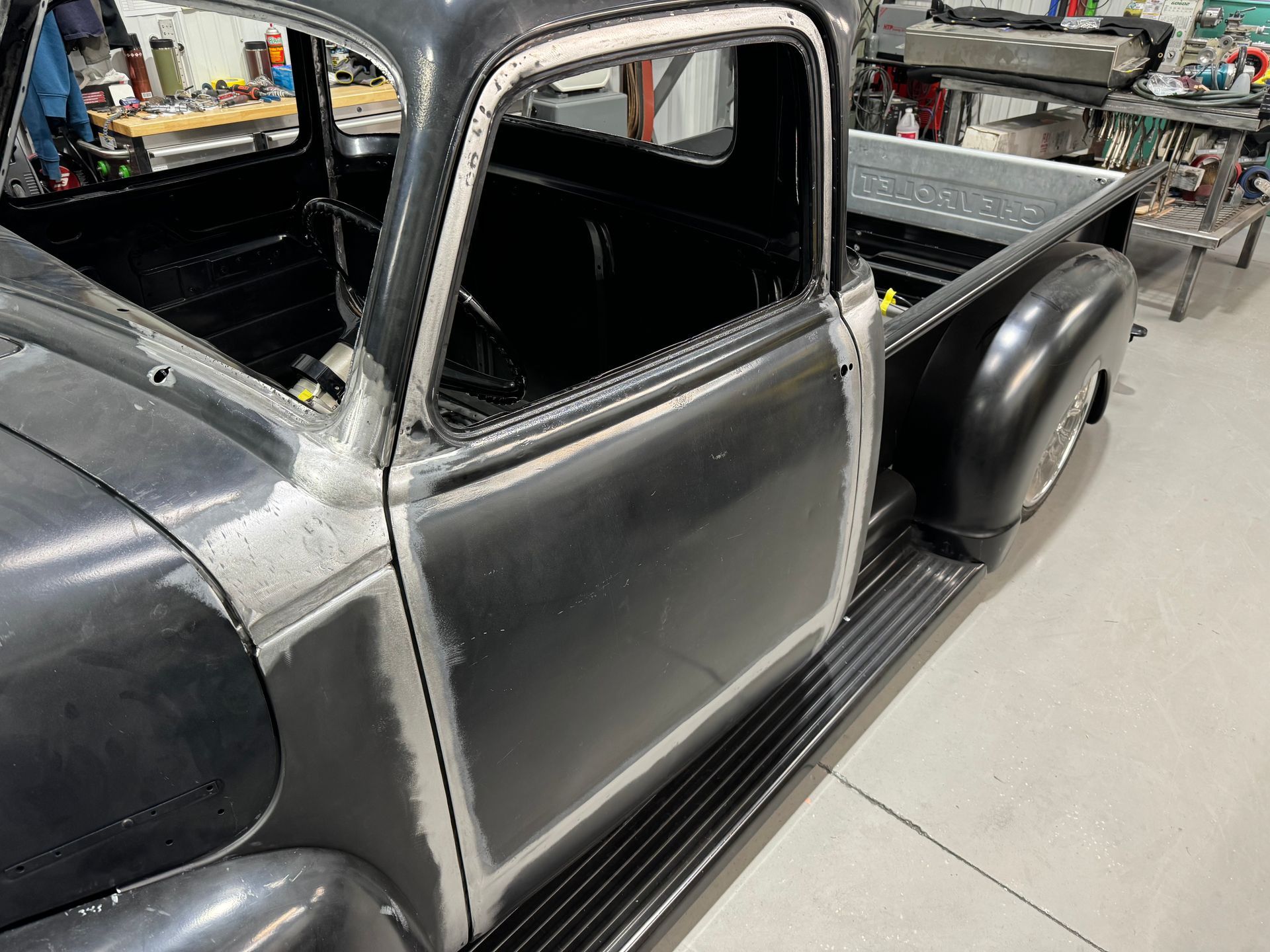 A black truck is sitting in a garage with the door open.