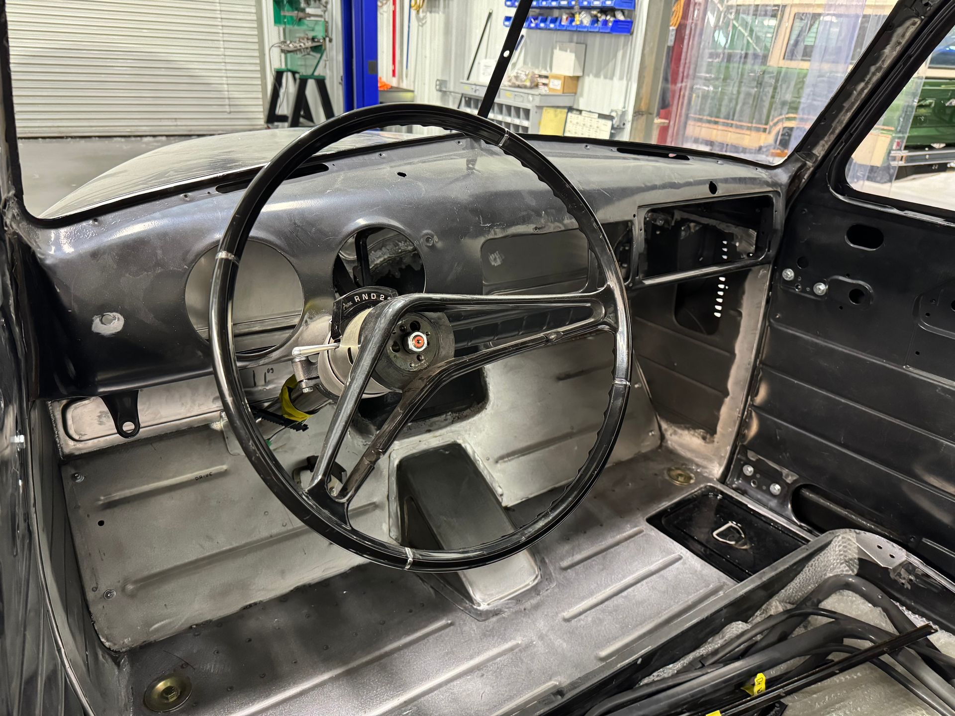 The interior of a car with a steering wheel in a garage.