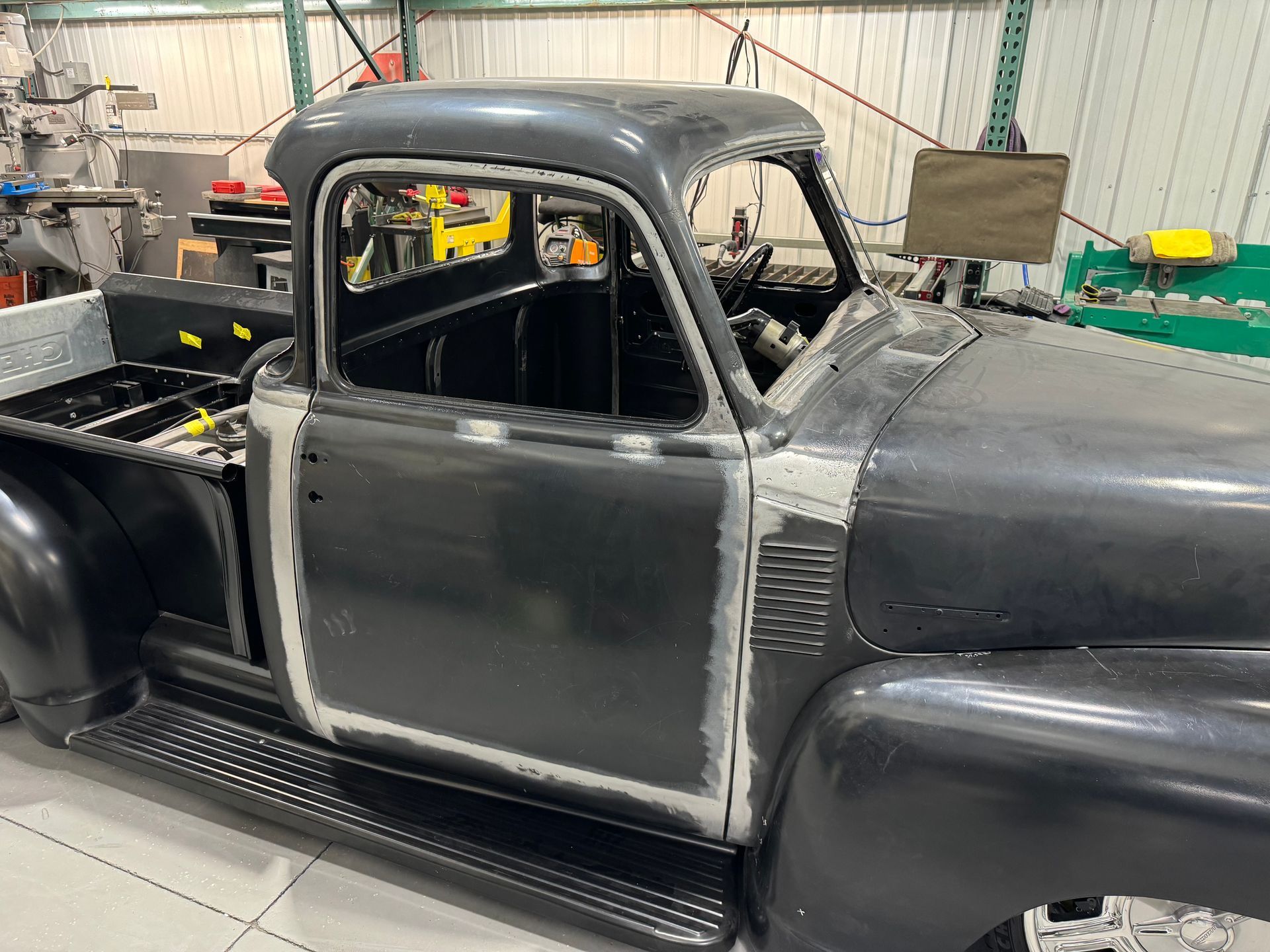 A black truck is being restored in a garage.