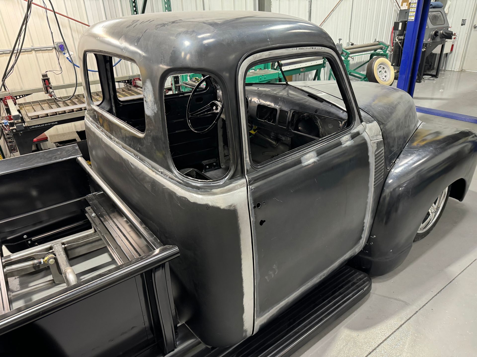 An old pickup truck is being built in a garage.