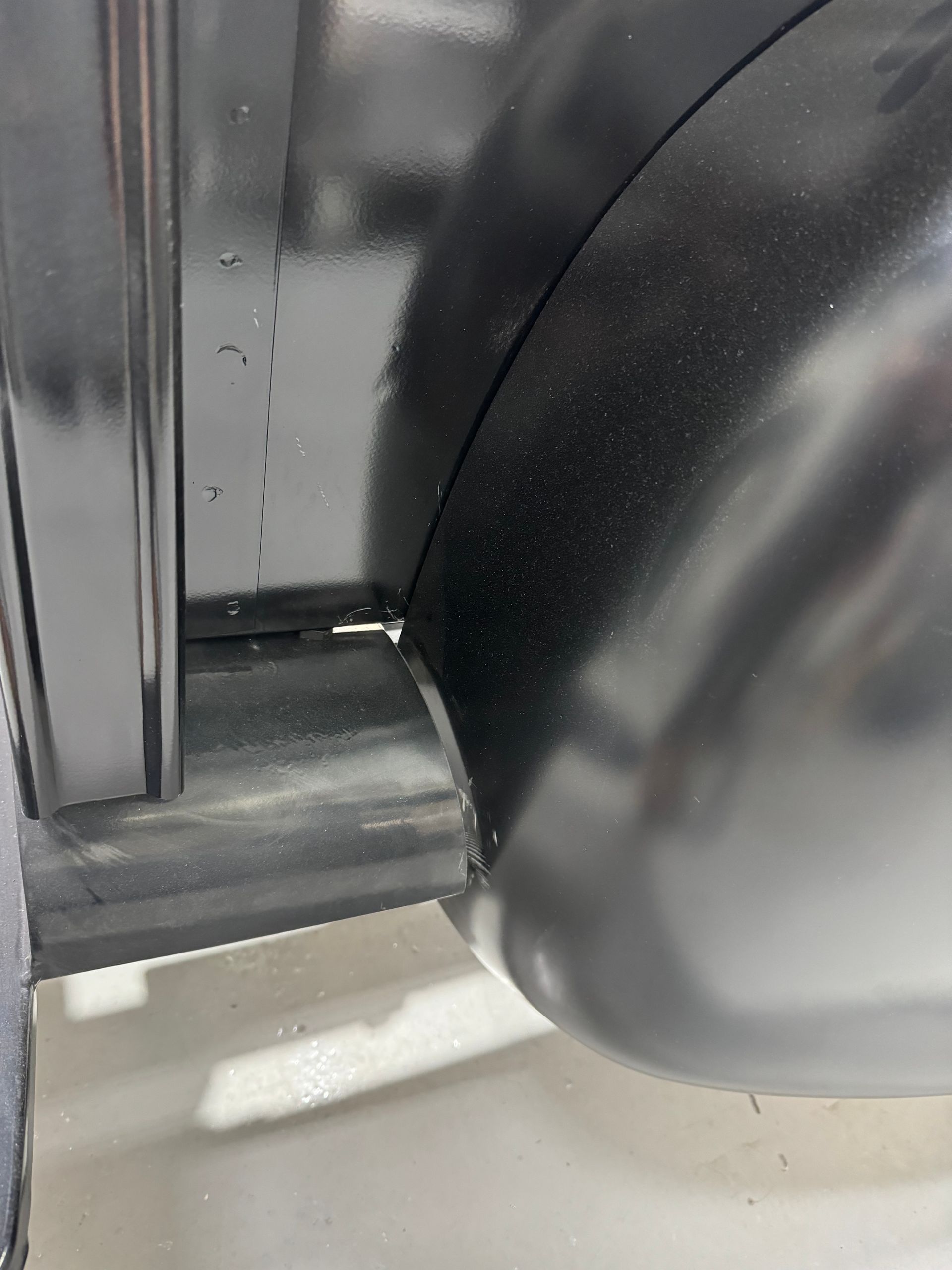 A close up of the fender of a black car.