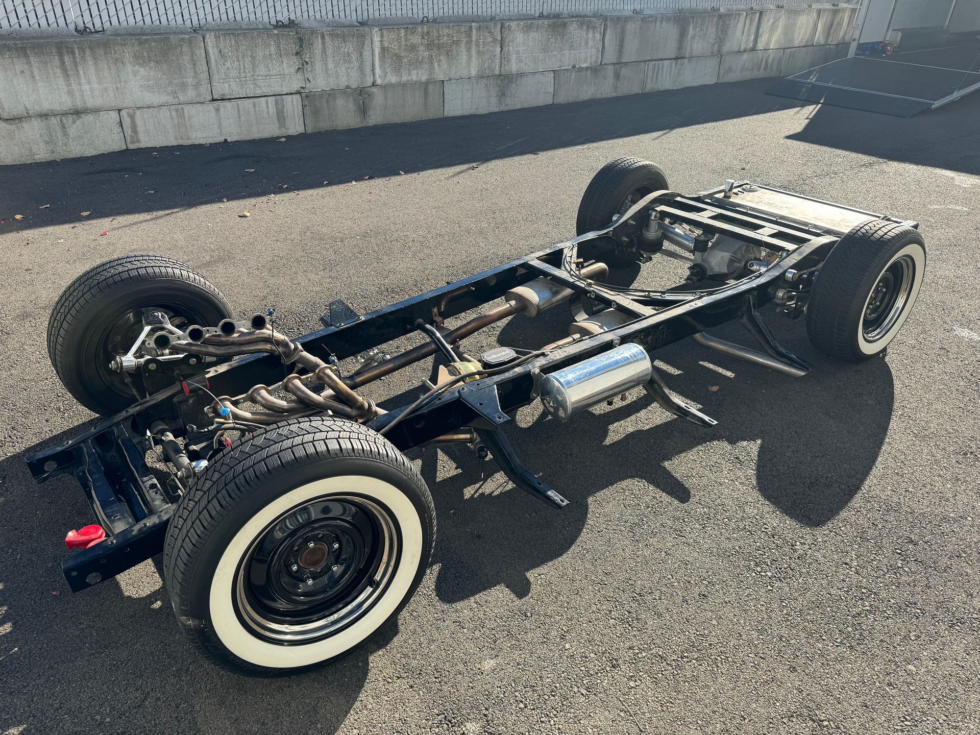 A truck chassis with white tires is sitting on the ground.
