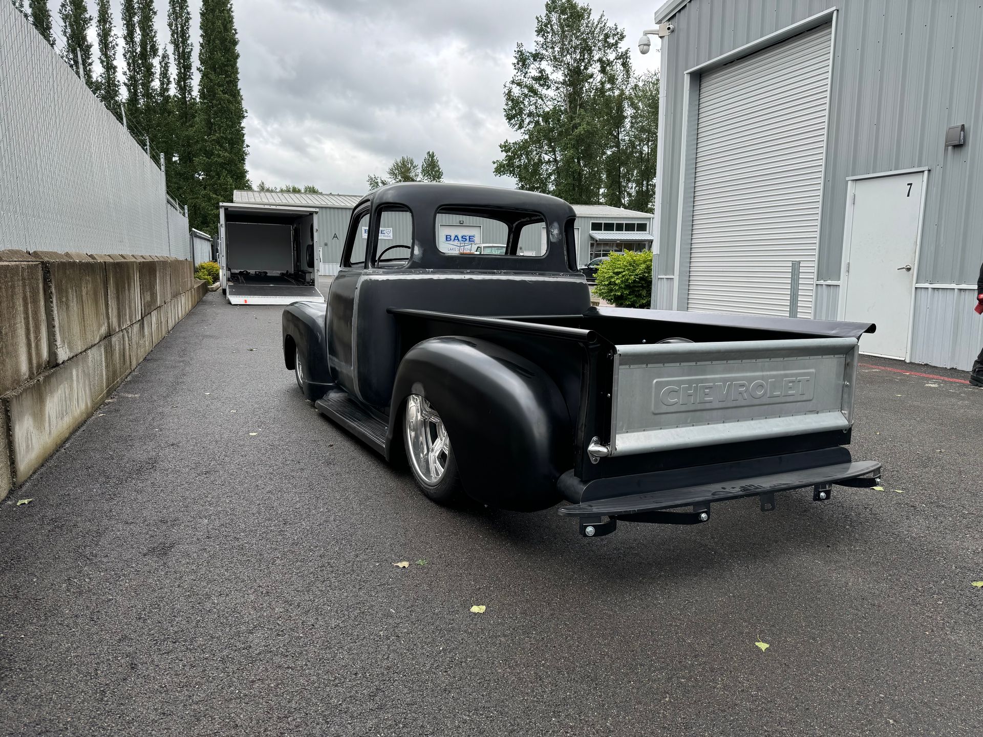 A black truck is parked in a parking lot next to a building.