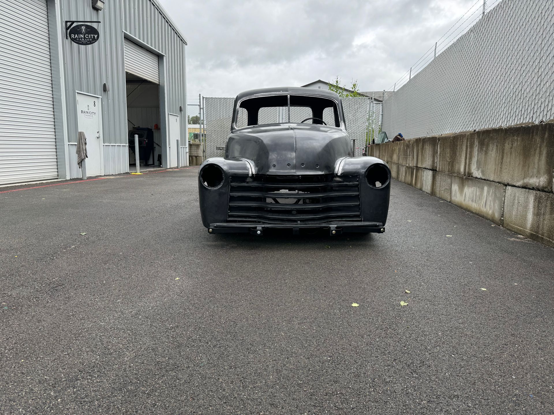 A black car is parked in a parking lot in front of a building.