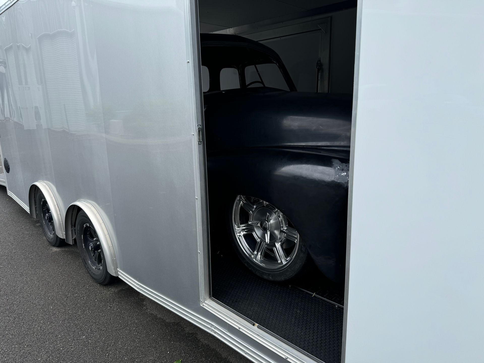A black car is sitting inside of a trailer.
