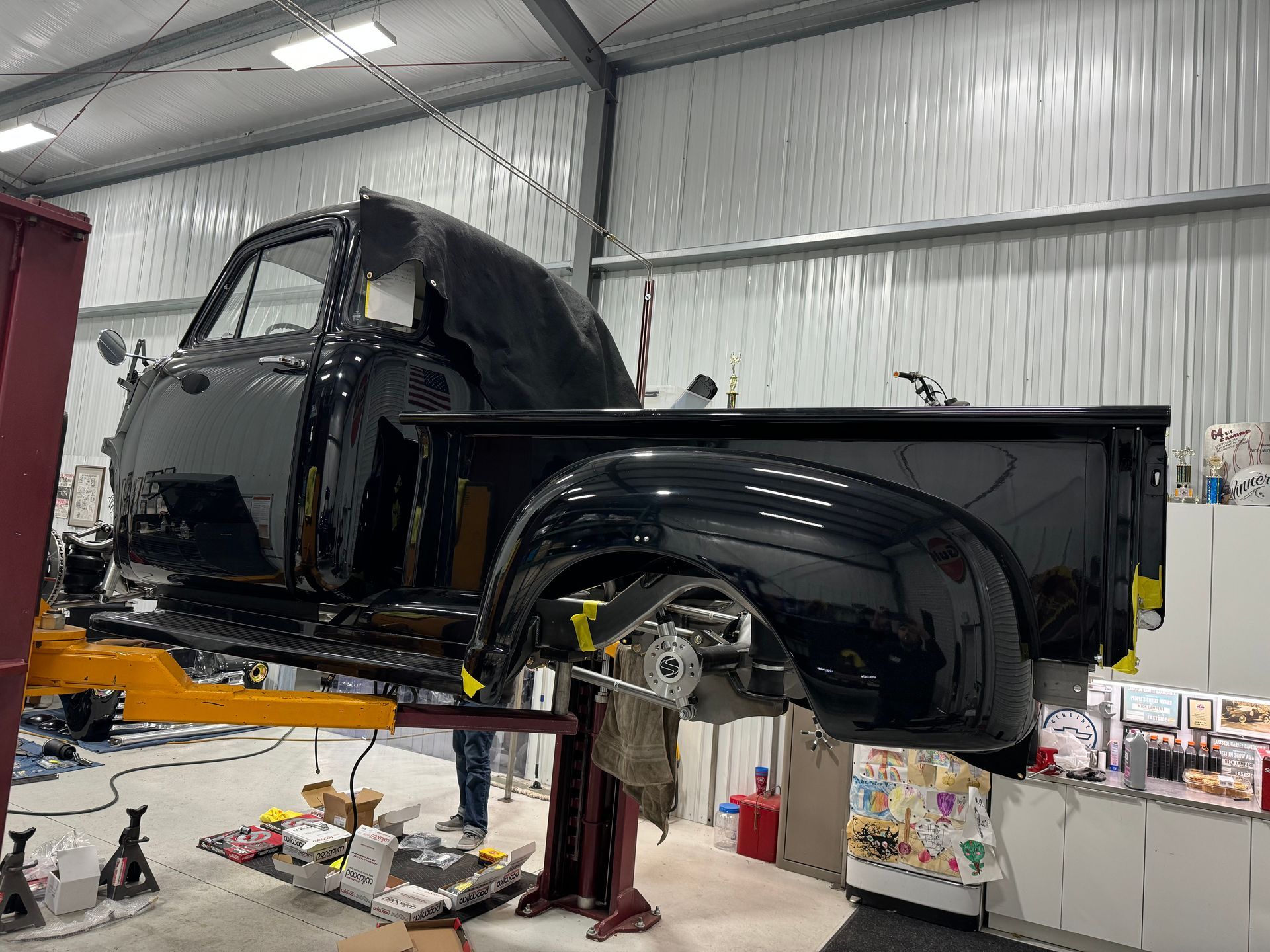 A black truck is sitting on a lift in a garage.
