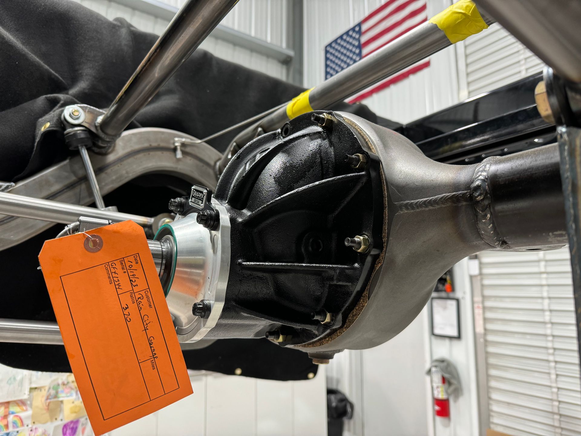 A close up of a rear axle with an orange tag attached to it