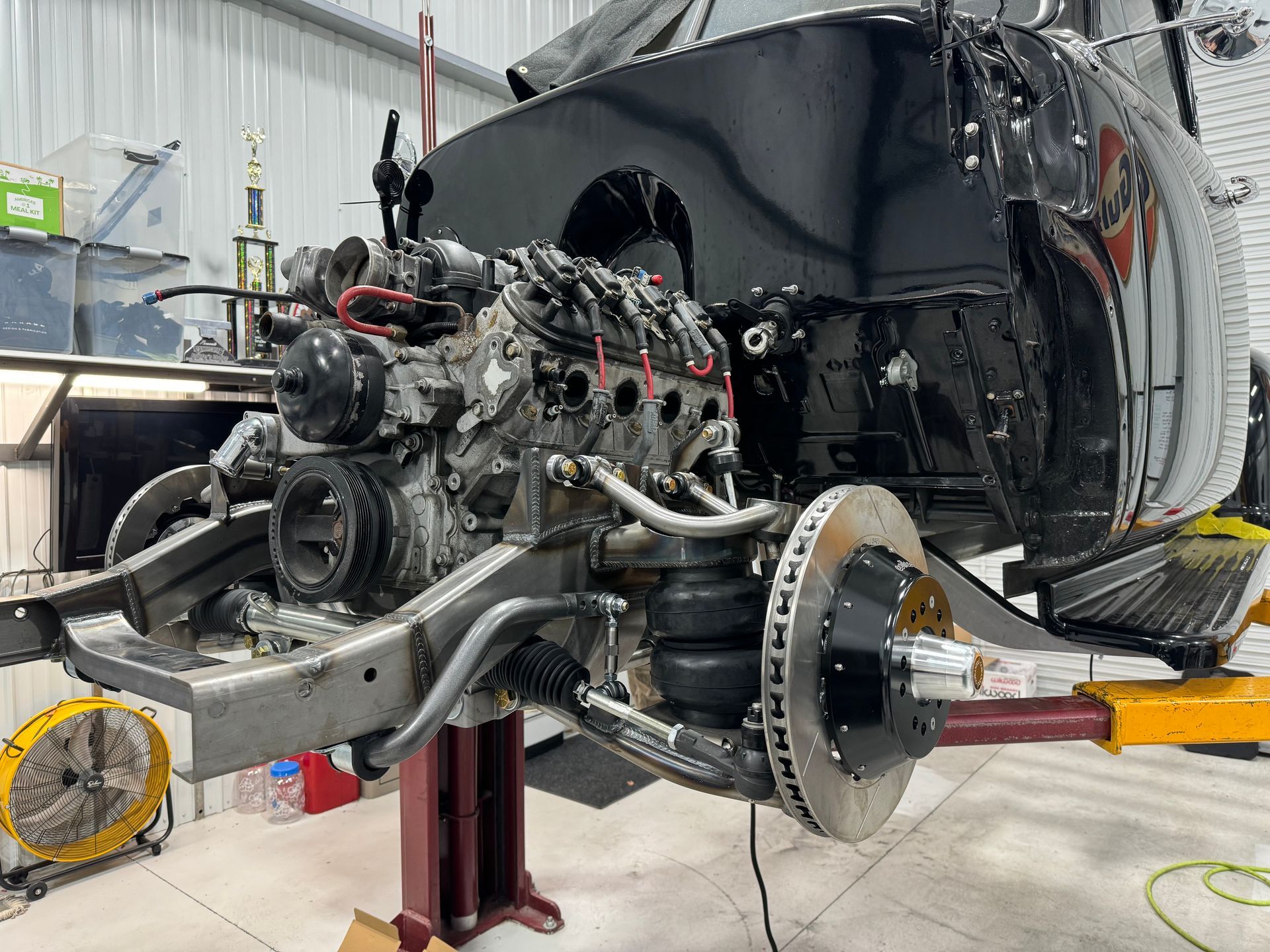 A car engine is sitting on a lift in a garage.