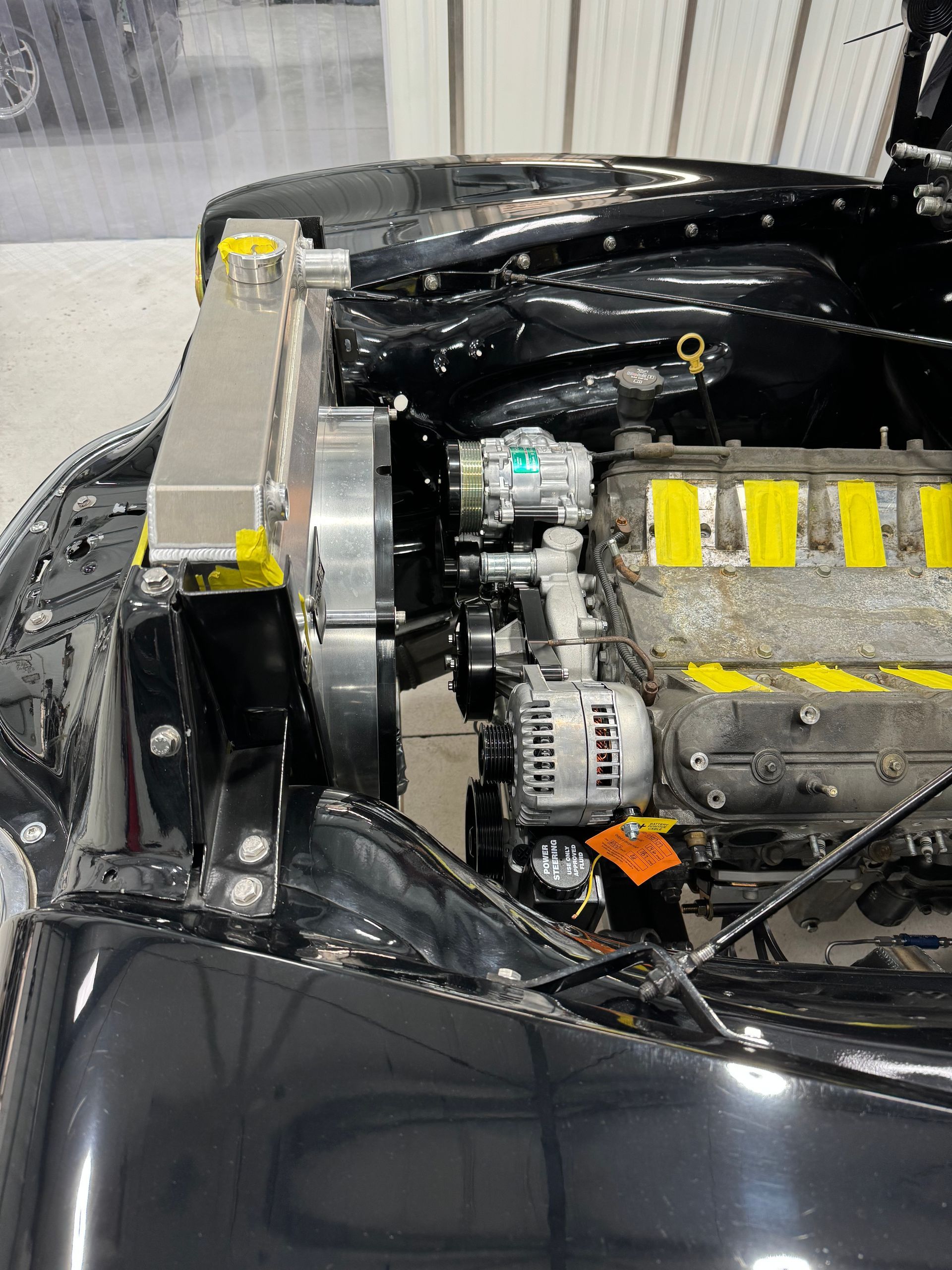 A black car with the hood open and the engine exposed.