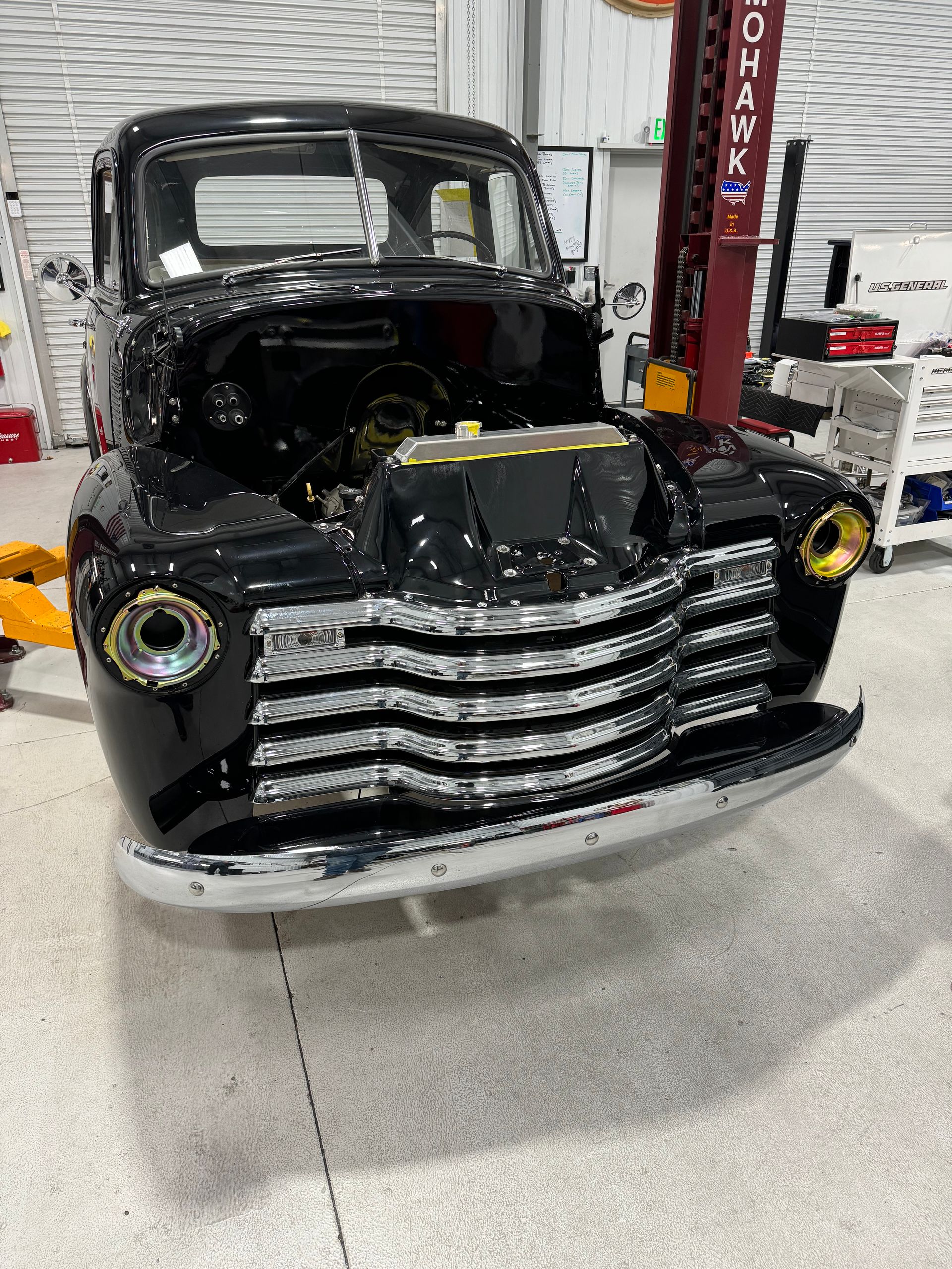 A black truck is parked in a garage with the hood open.