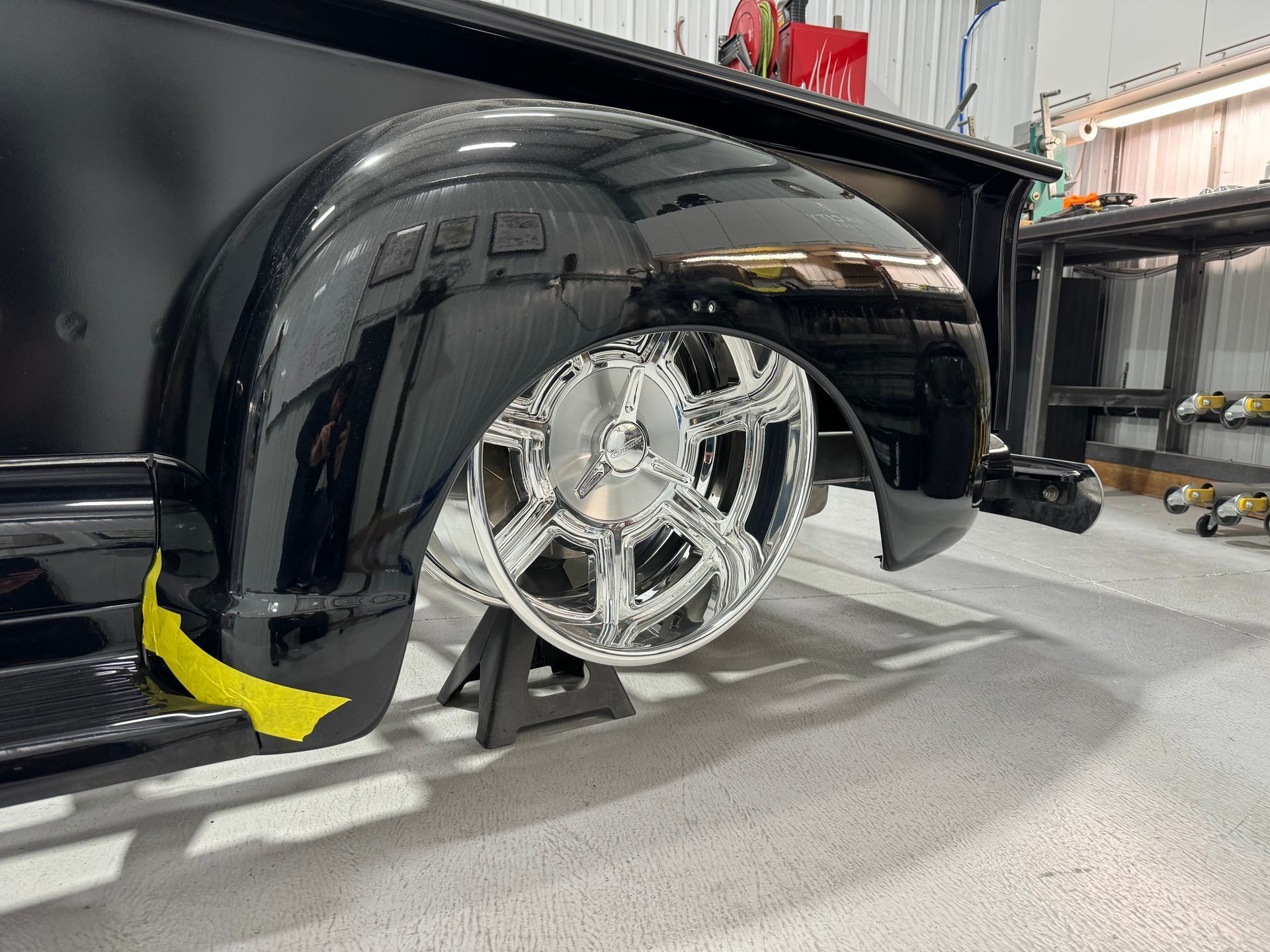 A black truck is sitting on a jack in a garage.