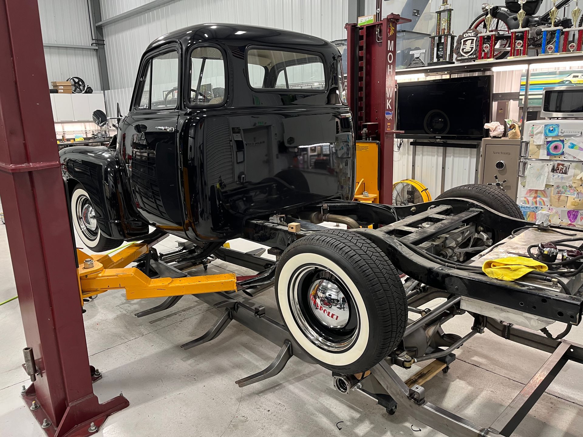 A black truck is sitting on a lift in a garage.
