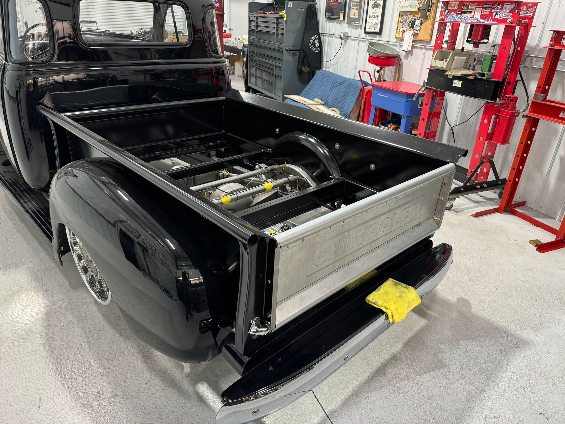 A black truck is parked in a garage with the bed open.
