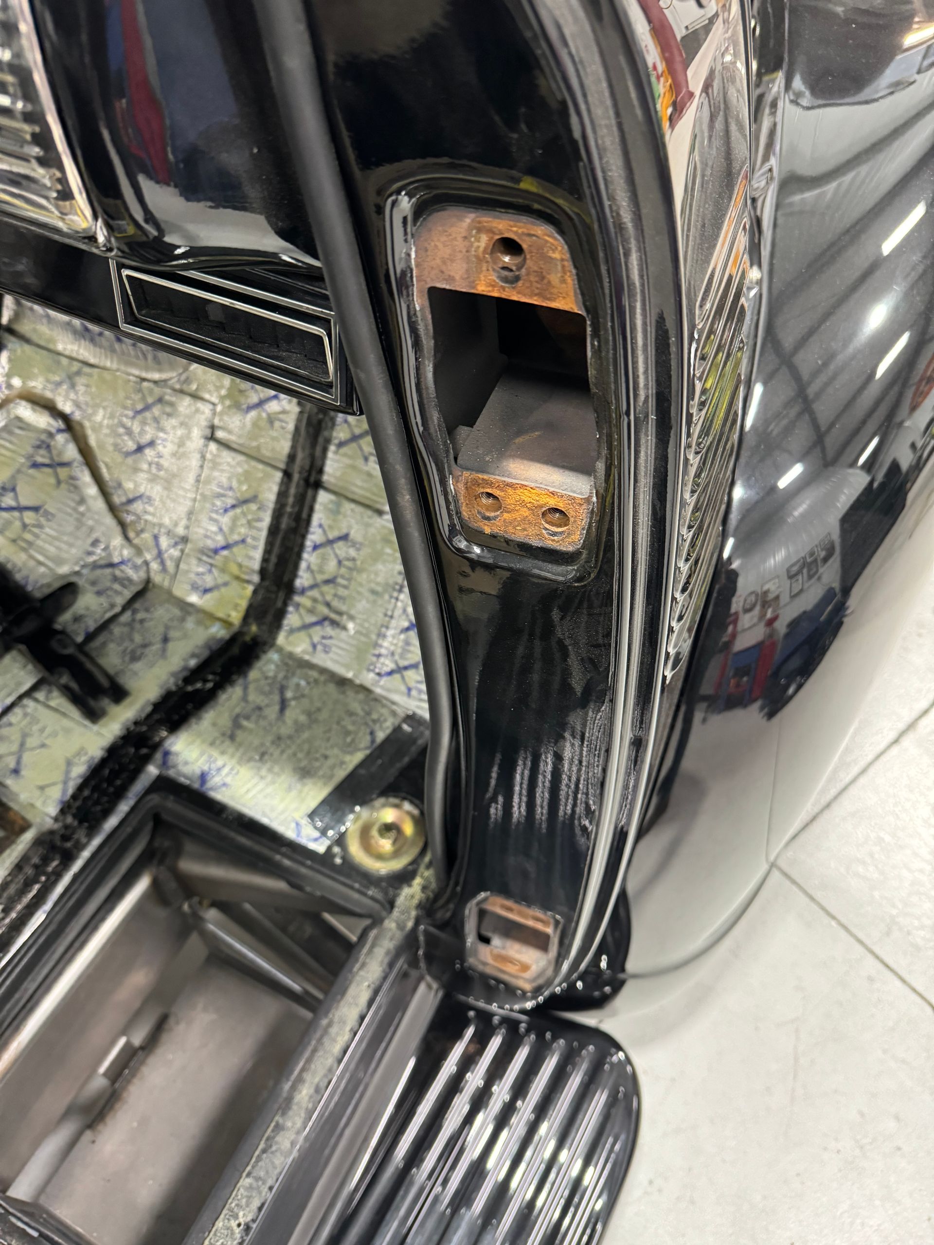 A black car is parked in a garage with the door open.