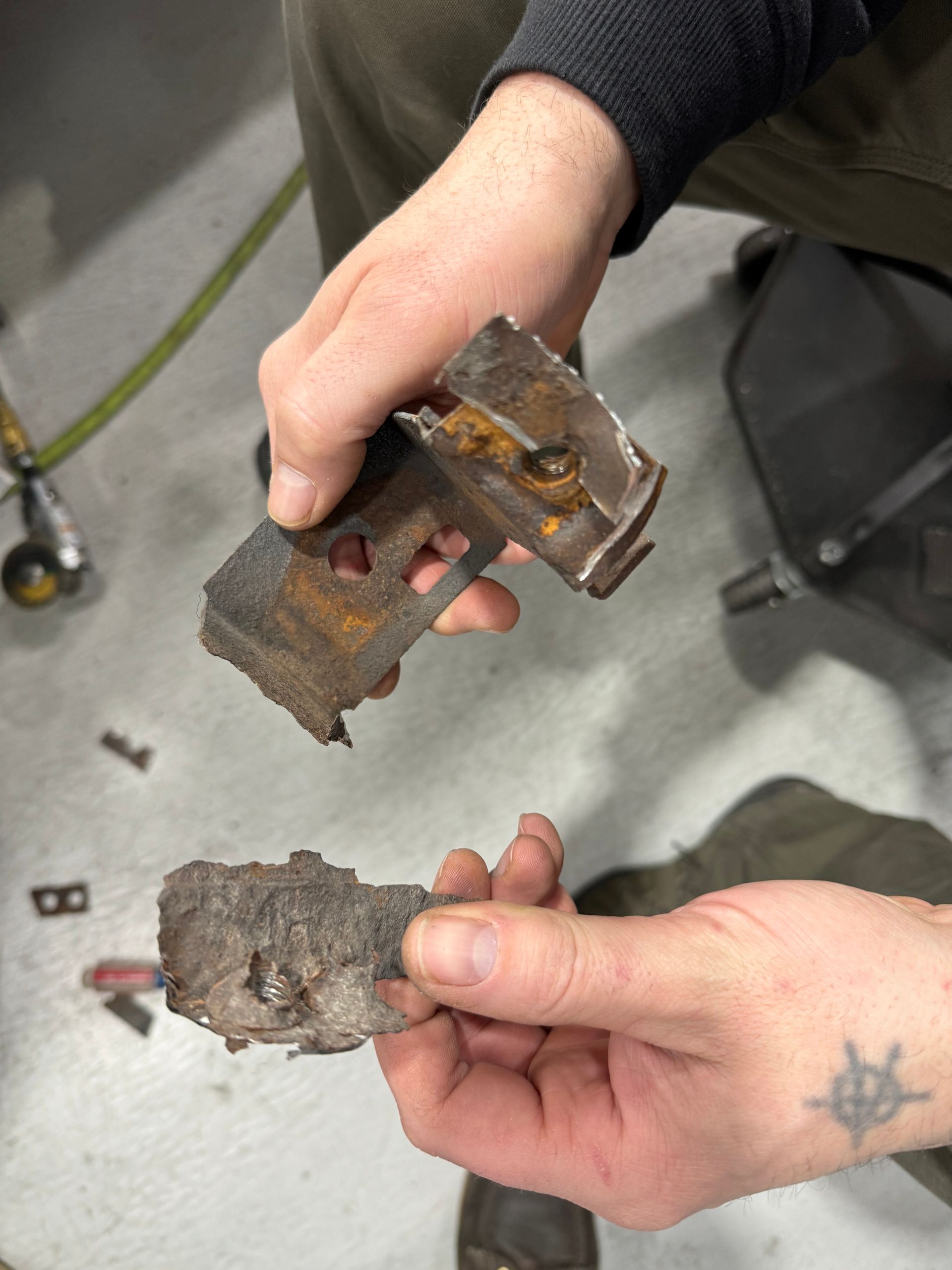 A person with a tattoo on their arm is holding a piece of metal