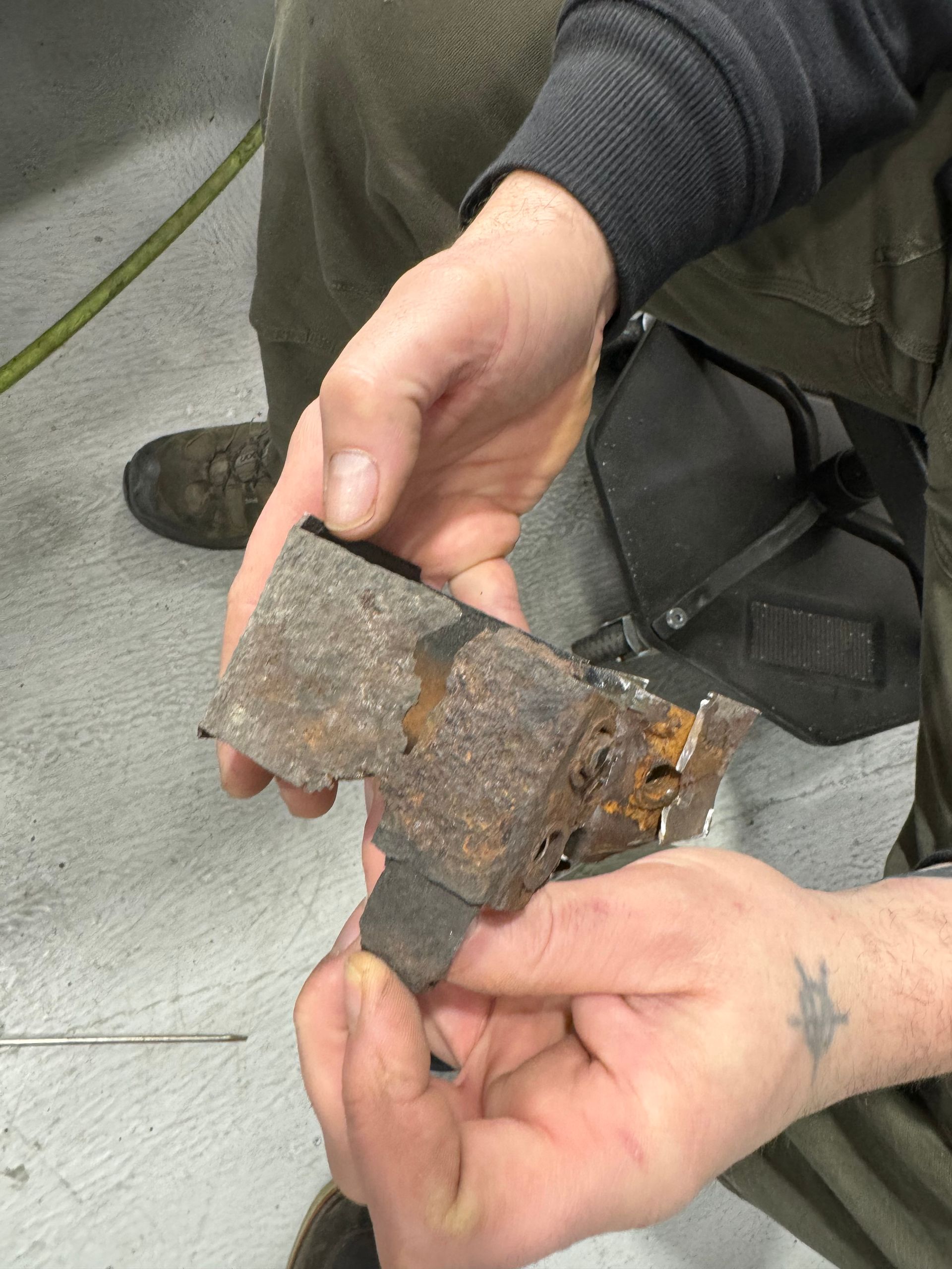 A person is holding a piece of rusty metal in their hands