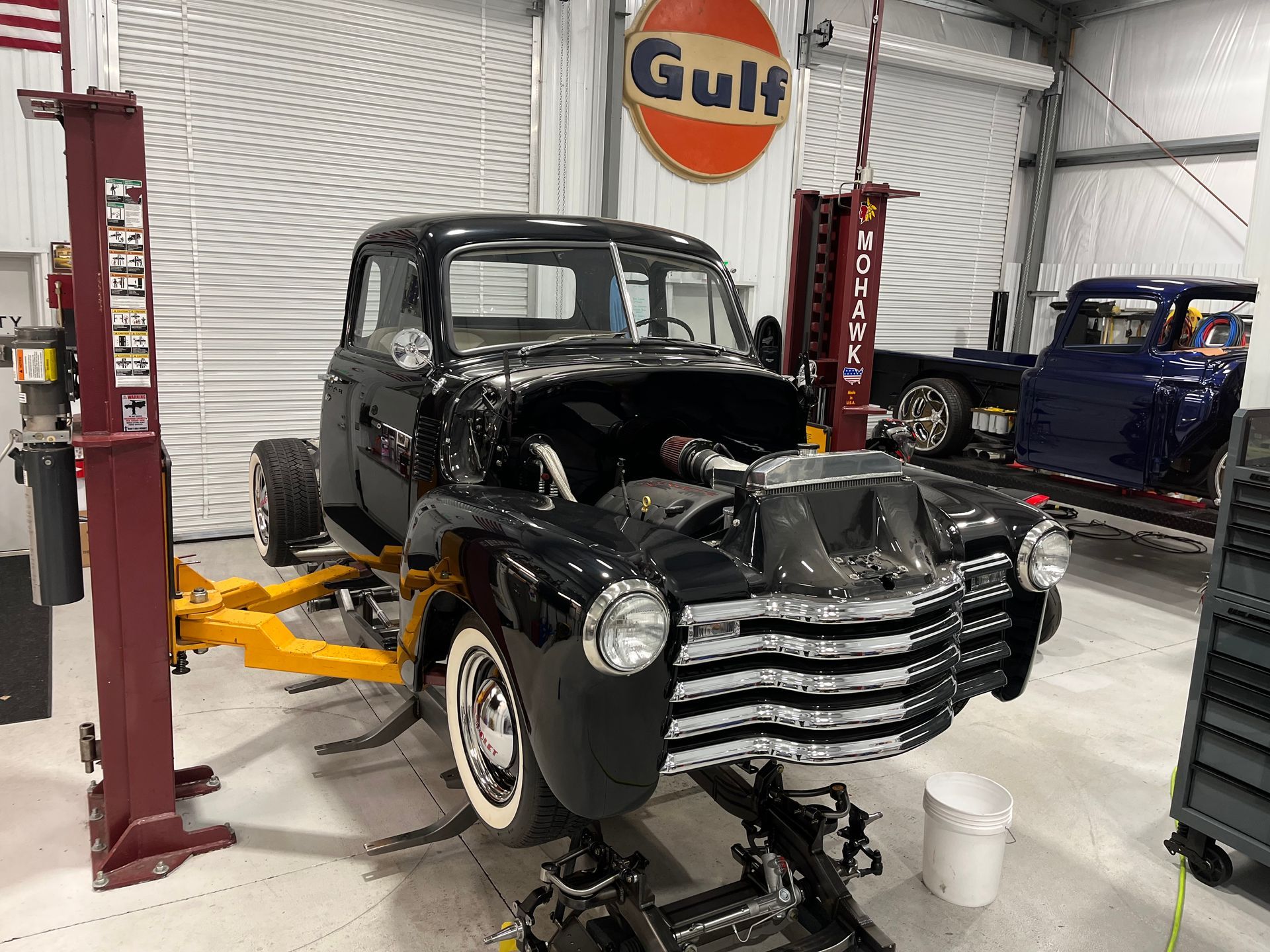 A black car is sitting on a lift in a garage.