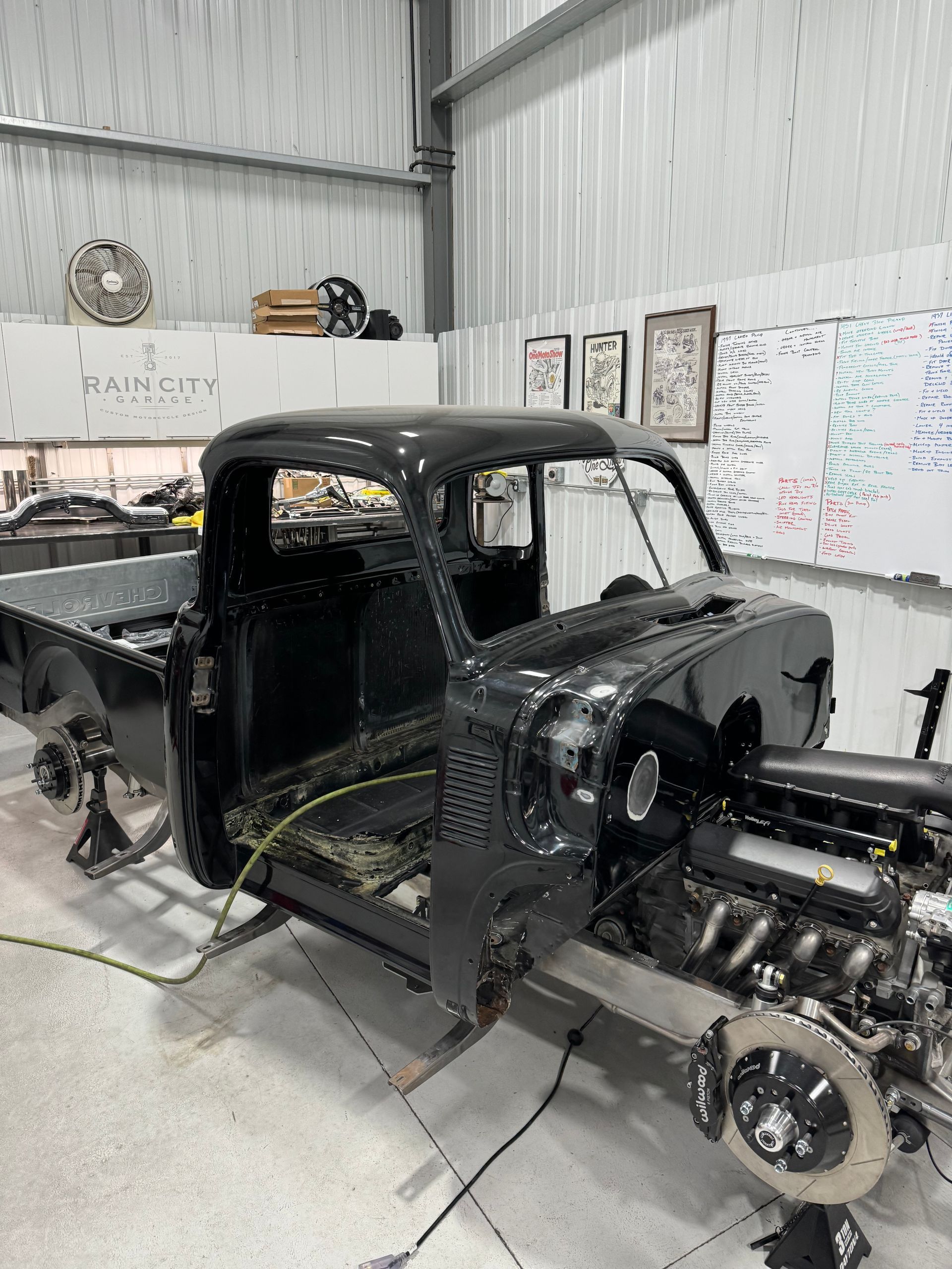 A black truck is being built in a garage.