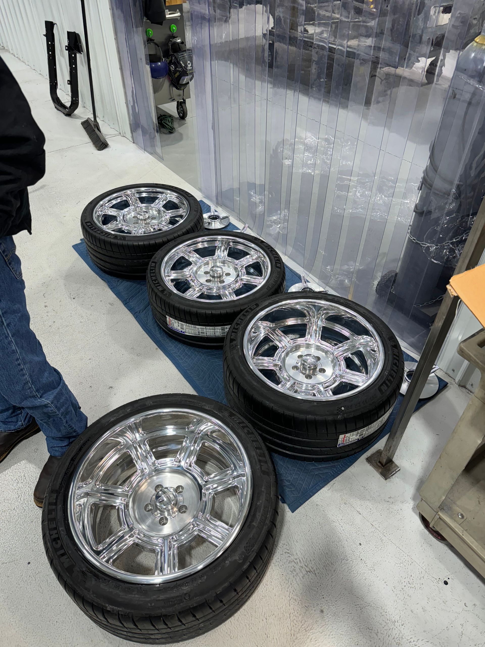 A person is standing next to a stack of wheels and tires.