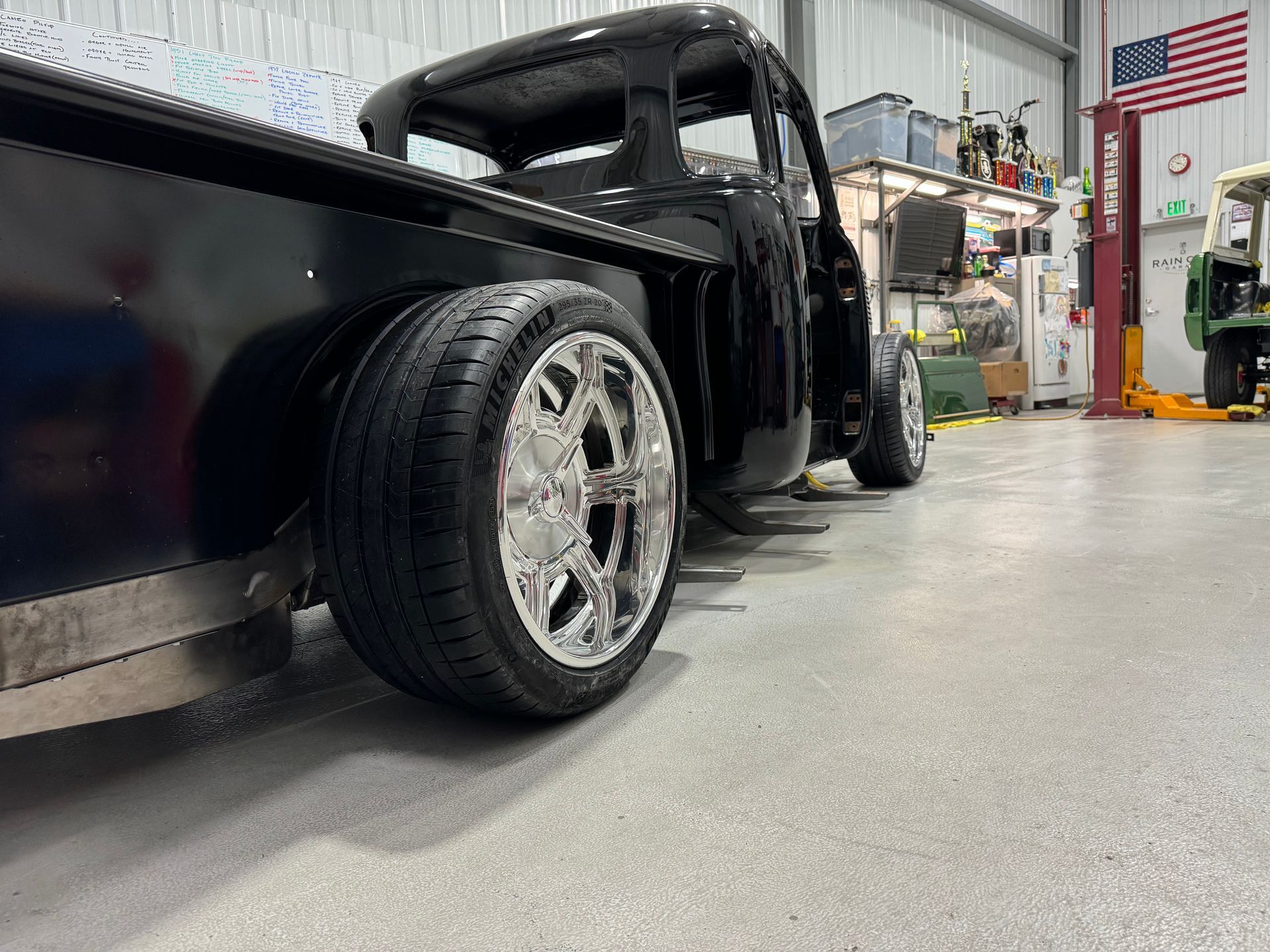 A black truck is parked in a garage next to an american flag.