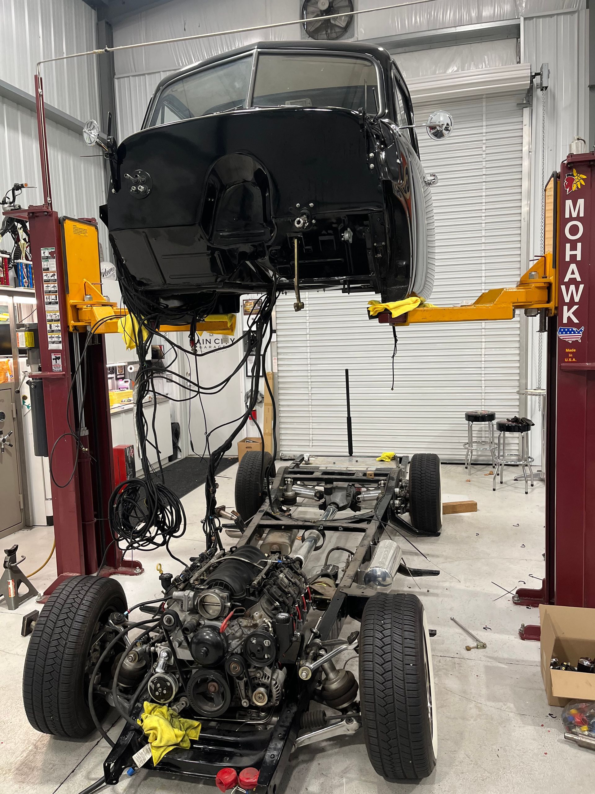A truck is being built in a garage on a lift.