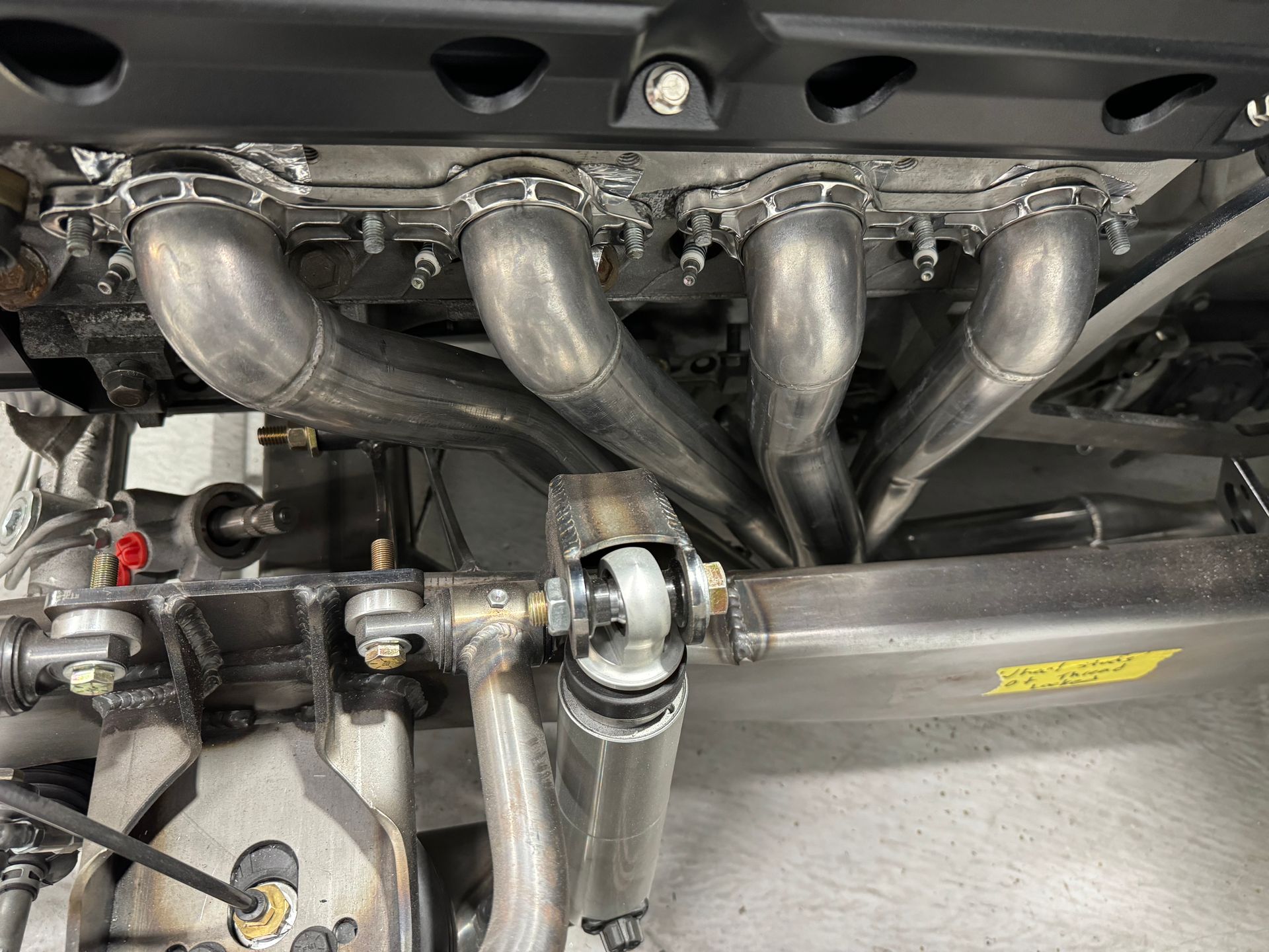 A close up of a stainless steel exhaust pipe on a car engine.
