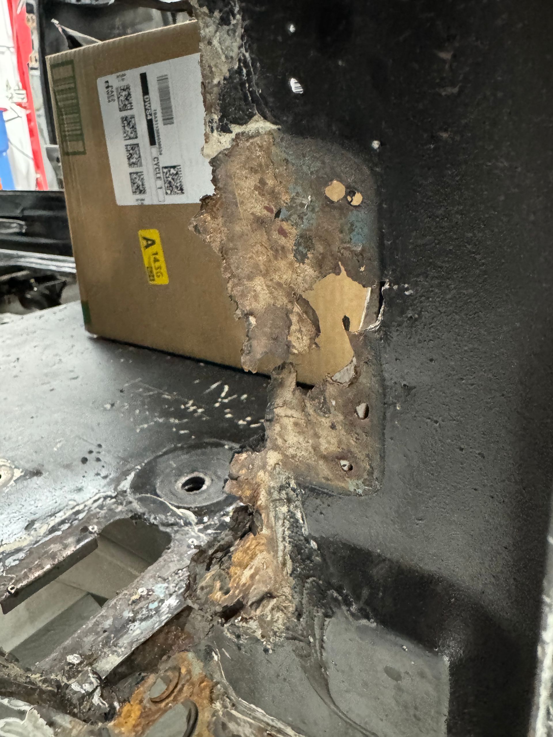 A cardboard box is sitting on top of a damaged piece of metal.