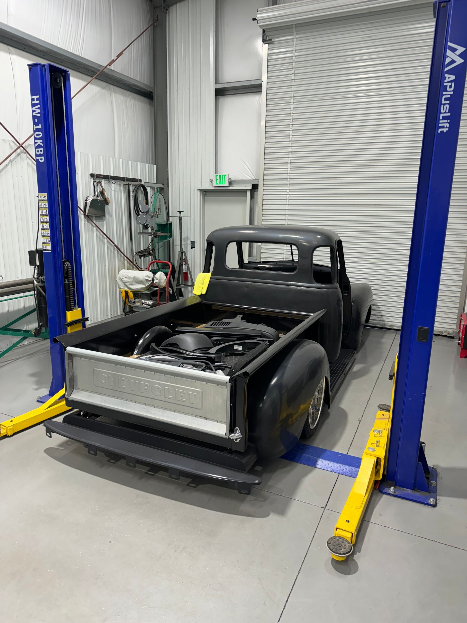 A truck is sitting on a lift in a garage.