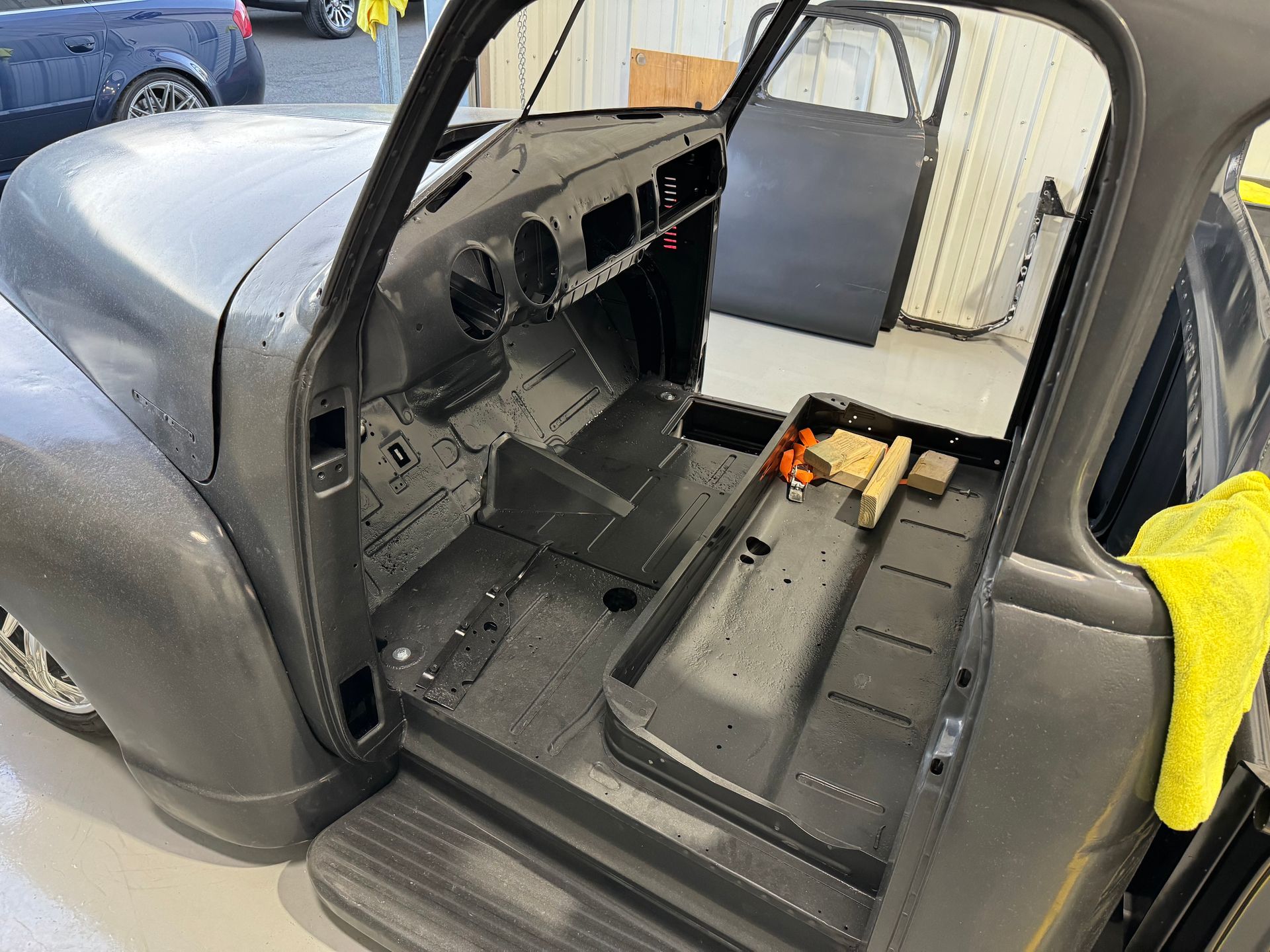 The inside of a truck with the door open and a yellow towel on the floor.
