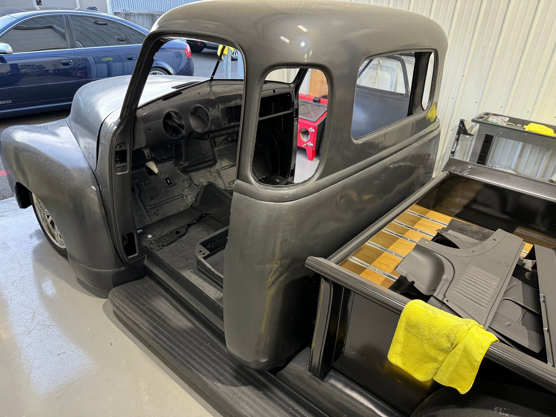 A gray truck is being restored in a garage.