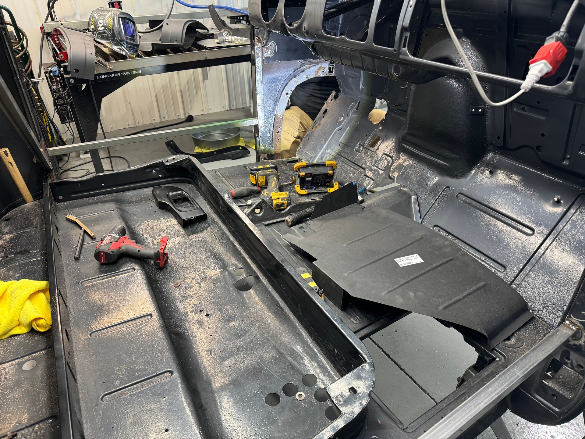 A car is being built in a garage with tools on the floor.