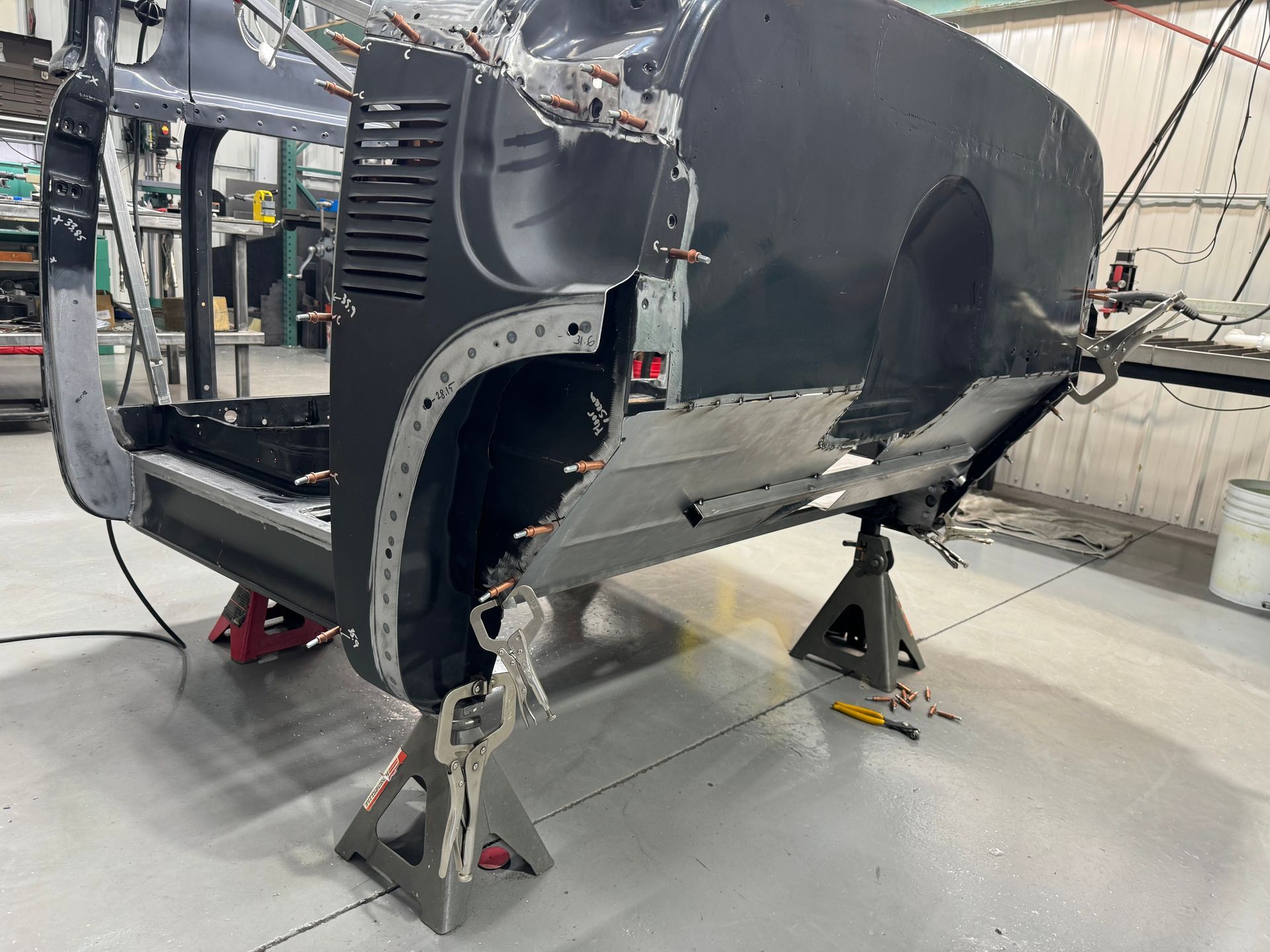 A car is being built in a garage and is sitting on jack stands.