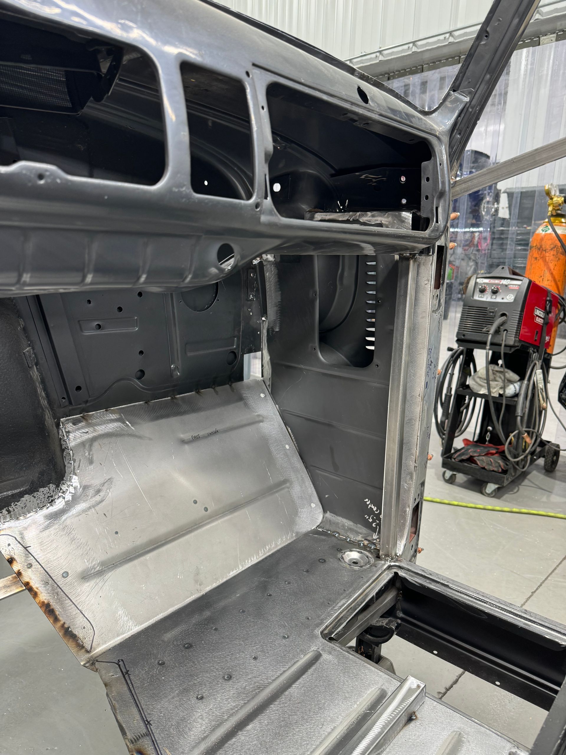 A man in a wheelchair is working on a car in a garage.