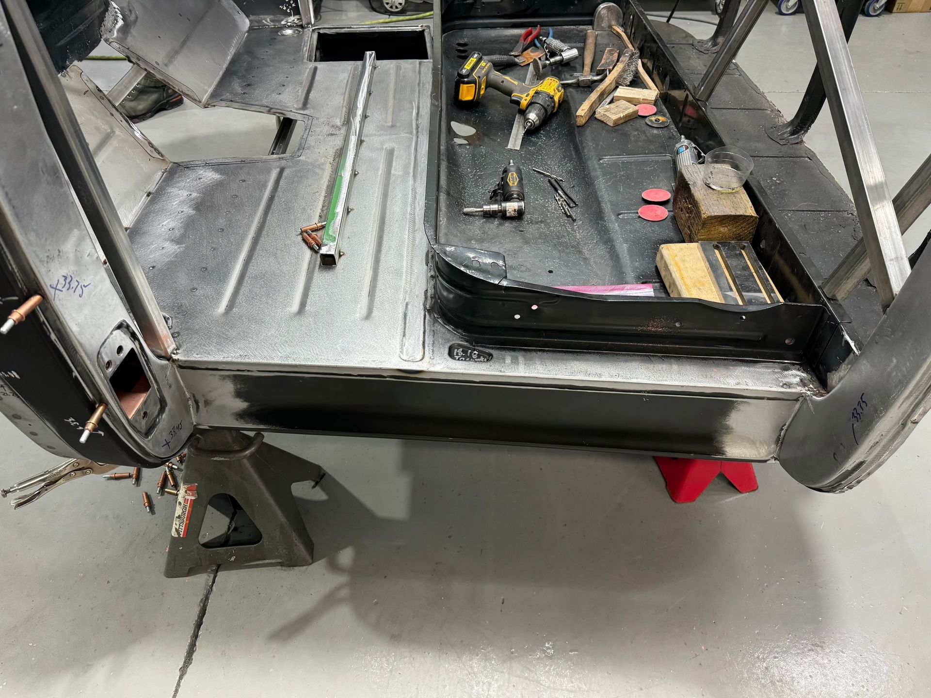 A car is being worked on in a garage with tools on the floor.