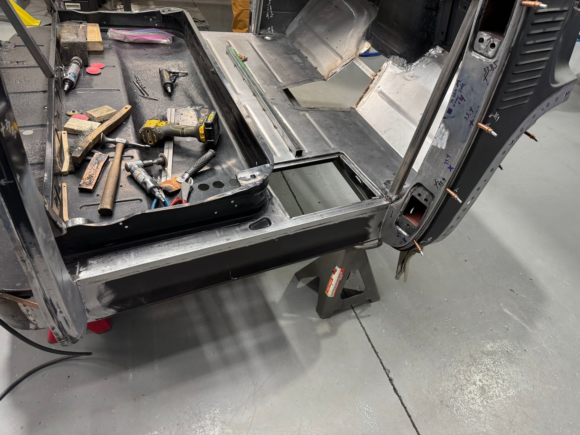 A car is being built in a garage with tools on the floor.