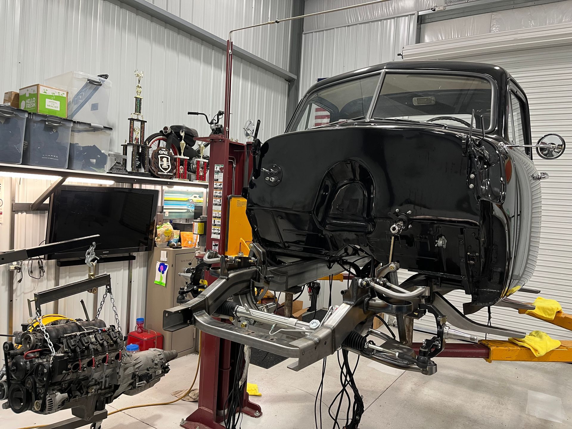 A black truck is sitting on a lift in a garage.