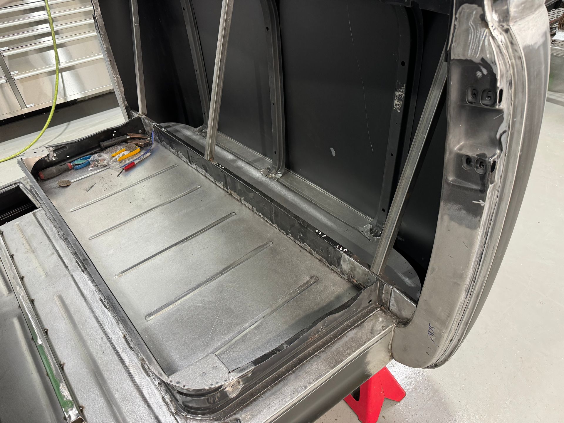 The trunk of a car is being worked on in a garage.