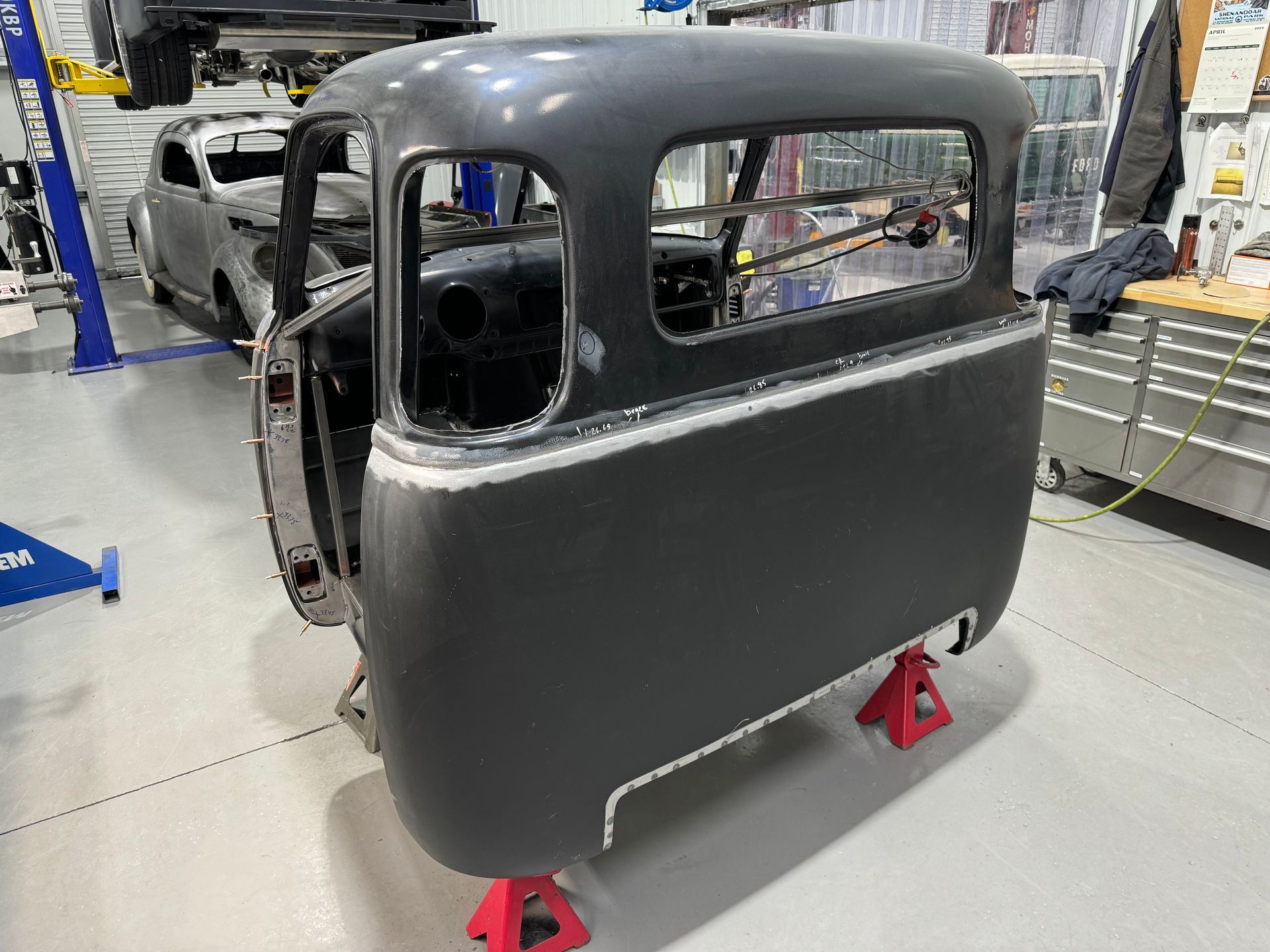 A car is being built in a garage and is sitting on jack stands.