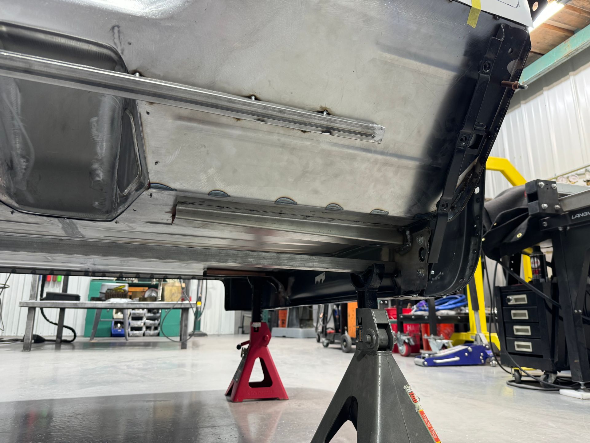 A car is sitting on a jack stand in a garage.