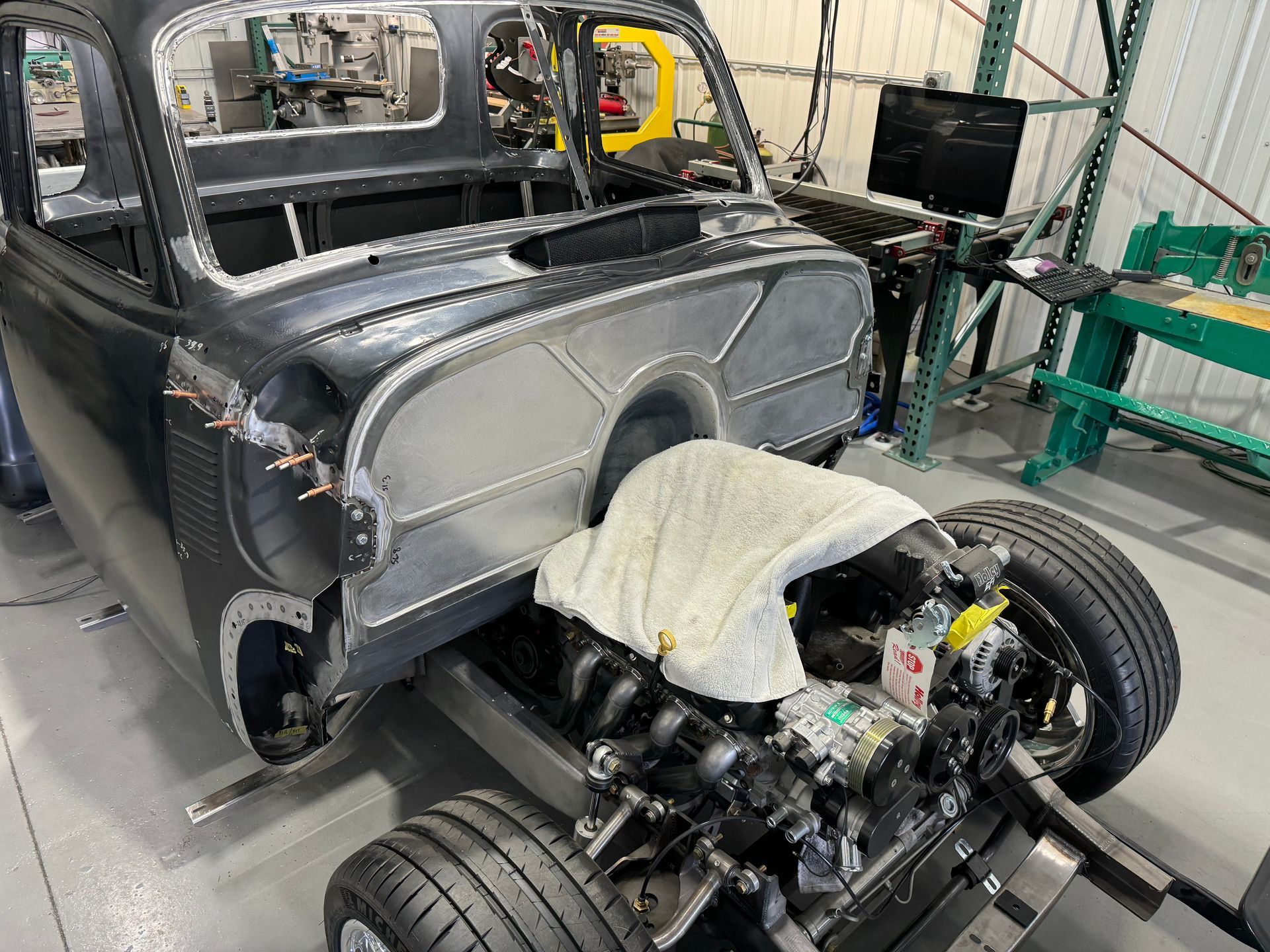 A car is being built in a garage with a towel on the engine.