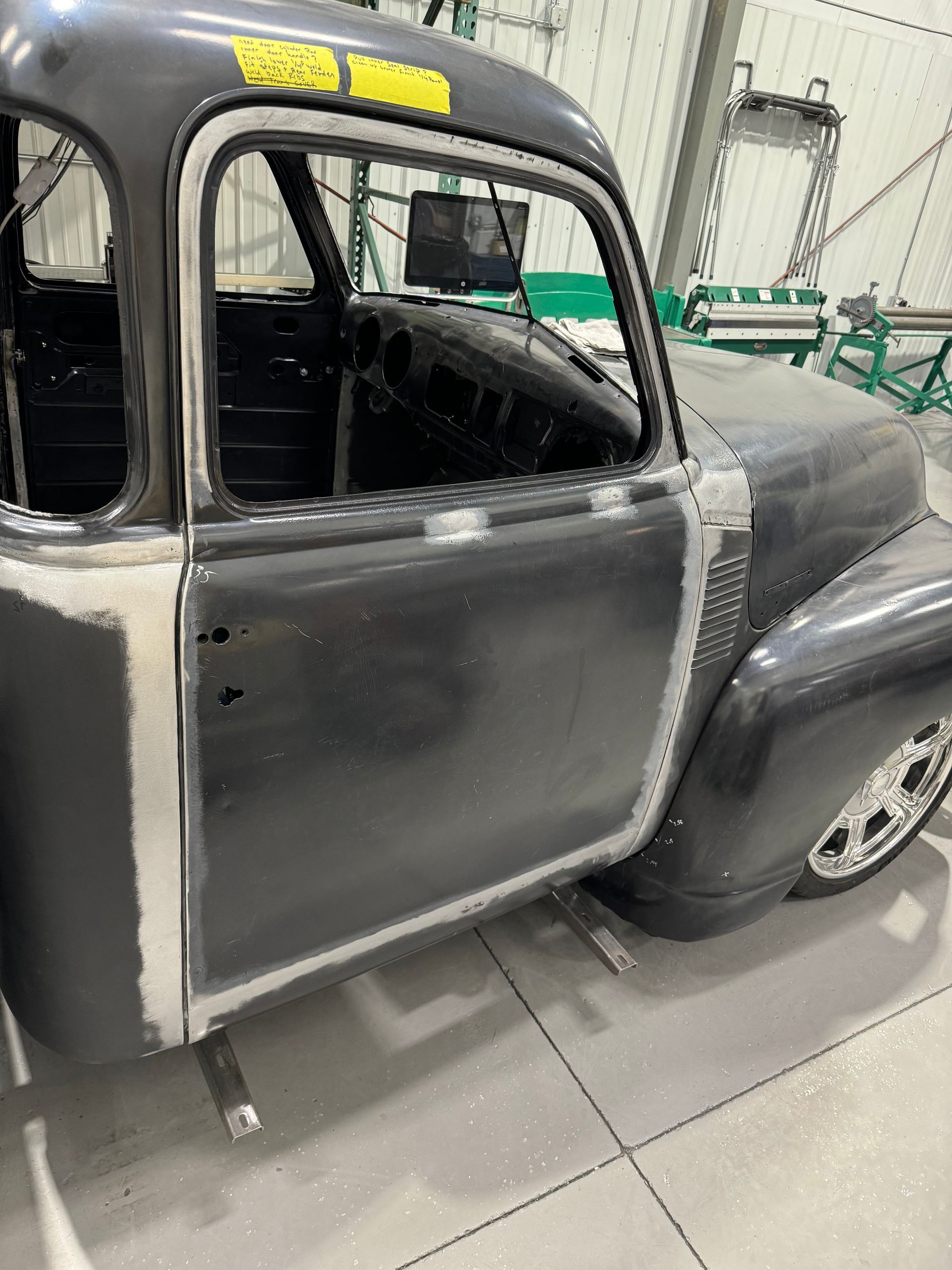 A black truck is sitting in a garage with its door open.
