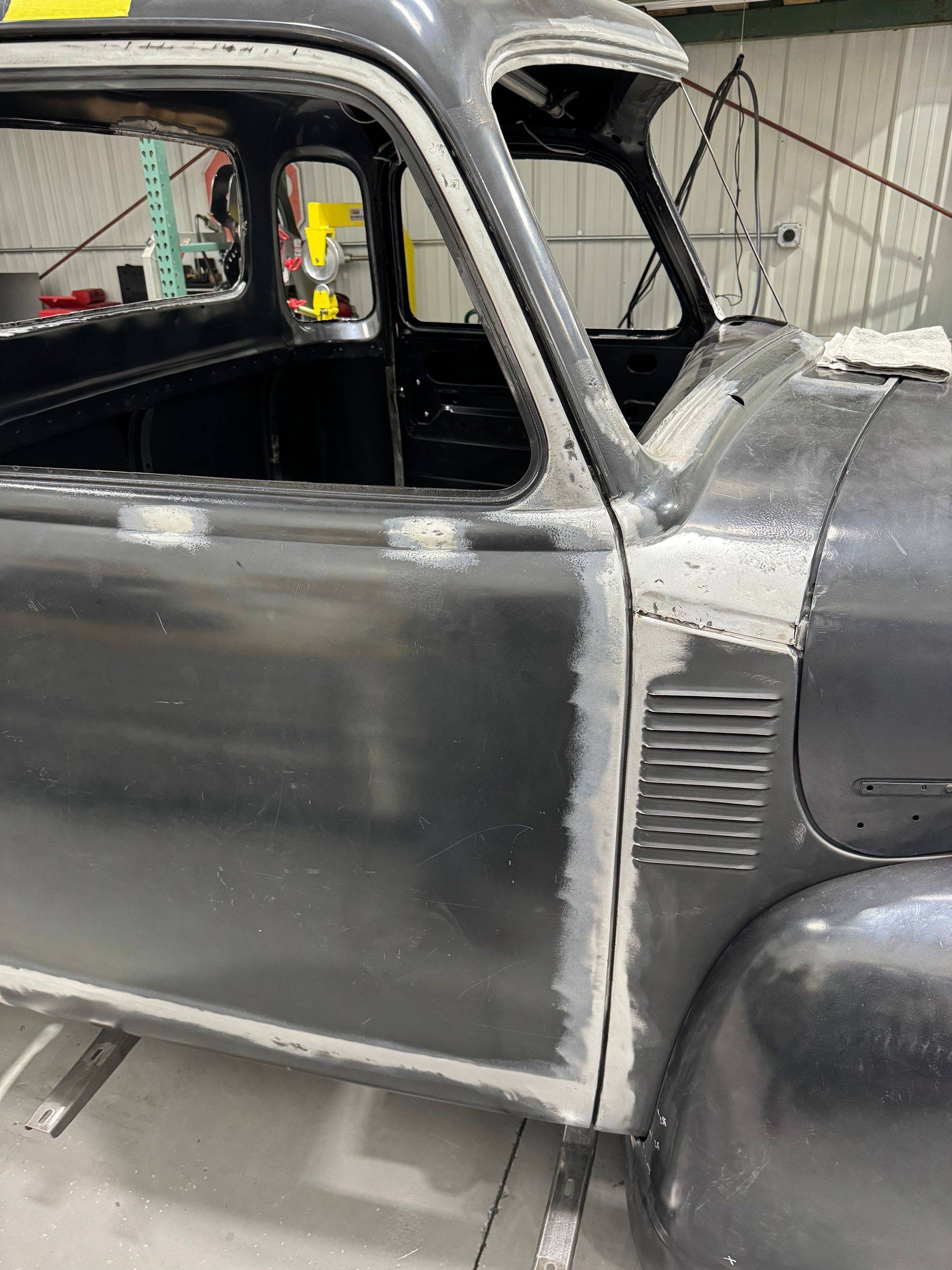 A black truck is being restored in a garage.