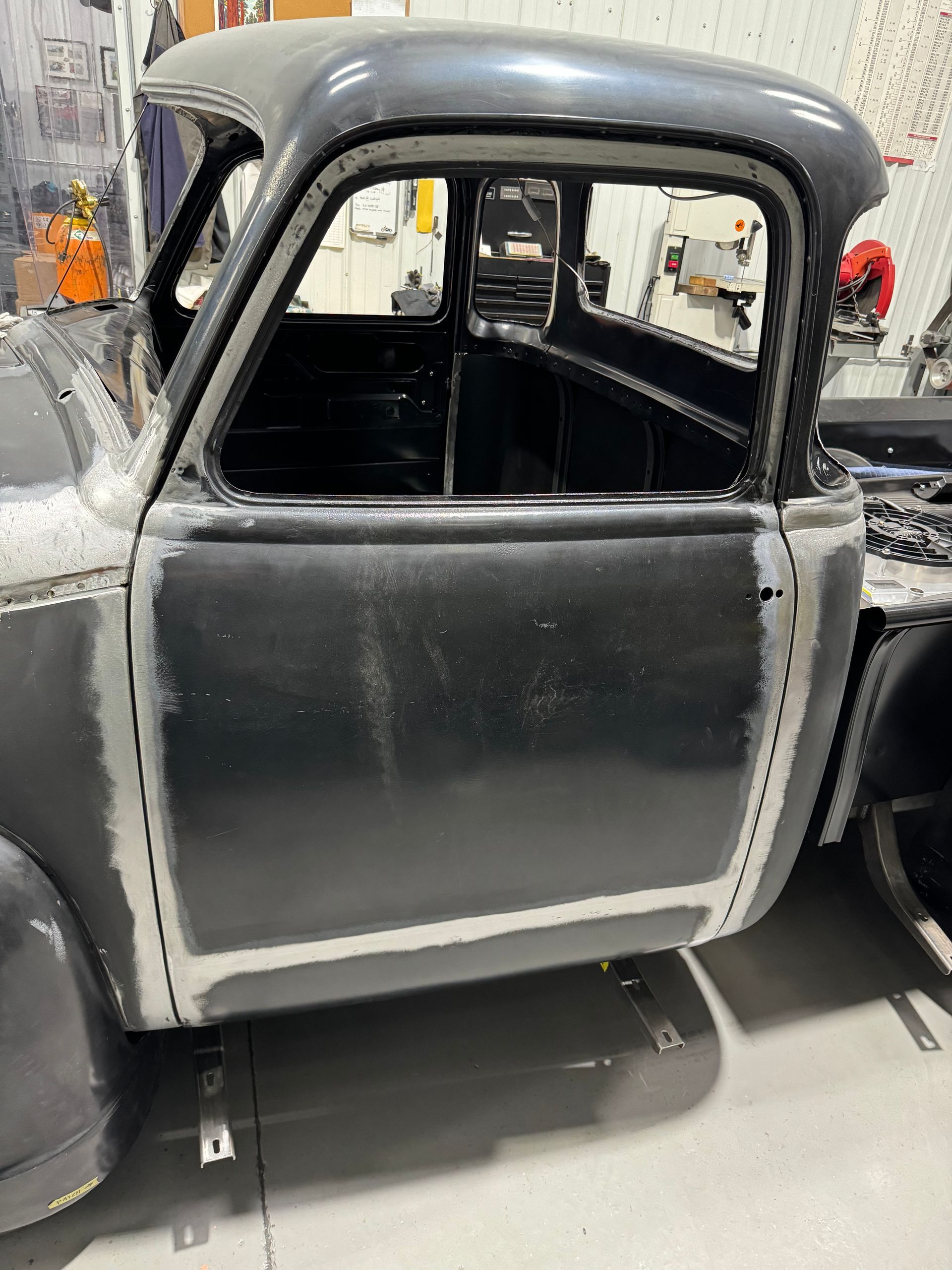 A black truck is sitting in a garage with the door open.