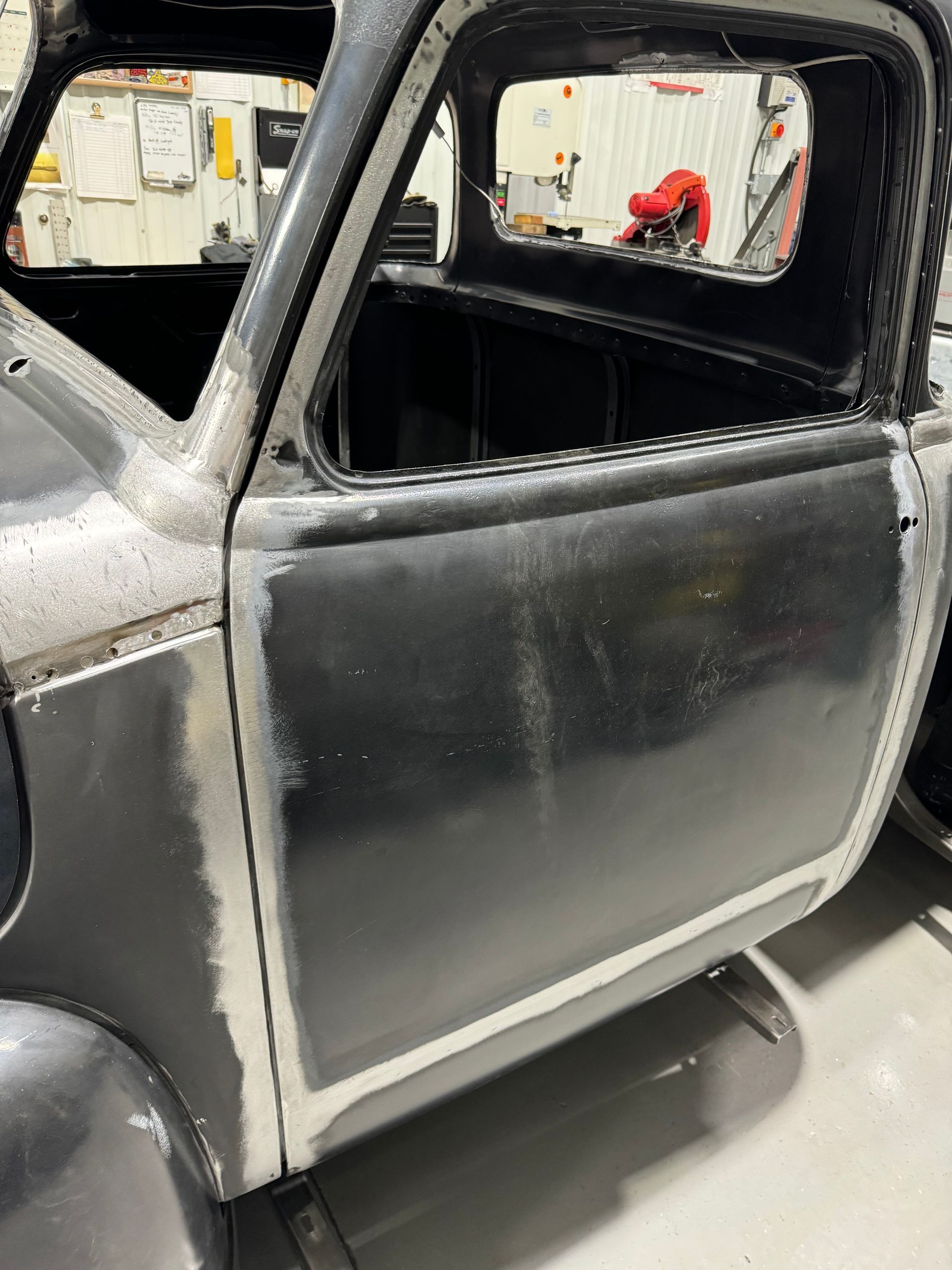 A black truck is sitting in a garage with the door open.