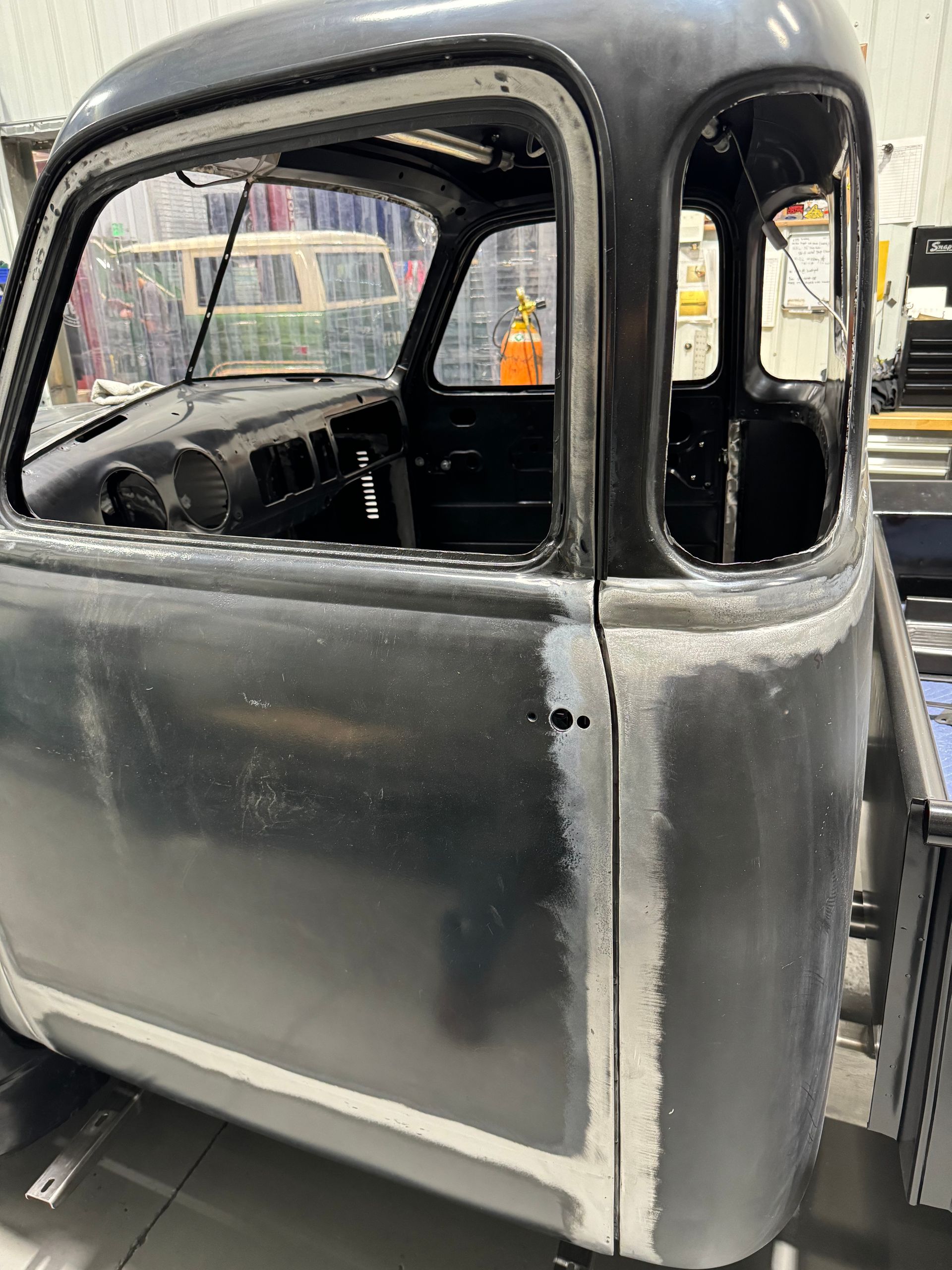 A black truck with a broken window is sitting in a garage.