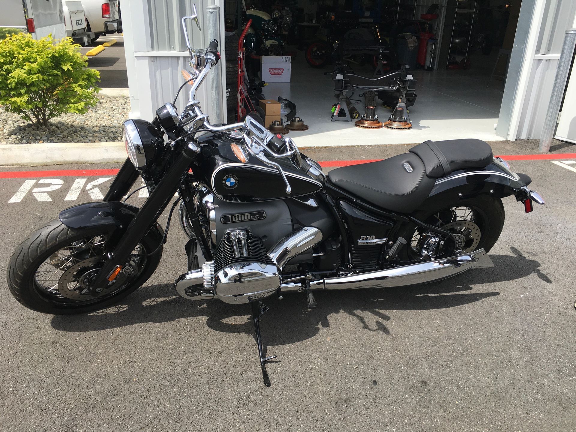 A black motorcycle is parked in front of a garage.
