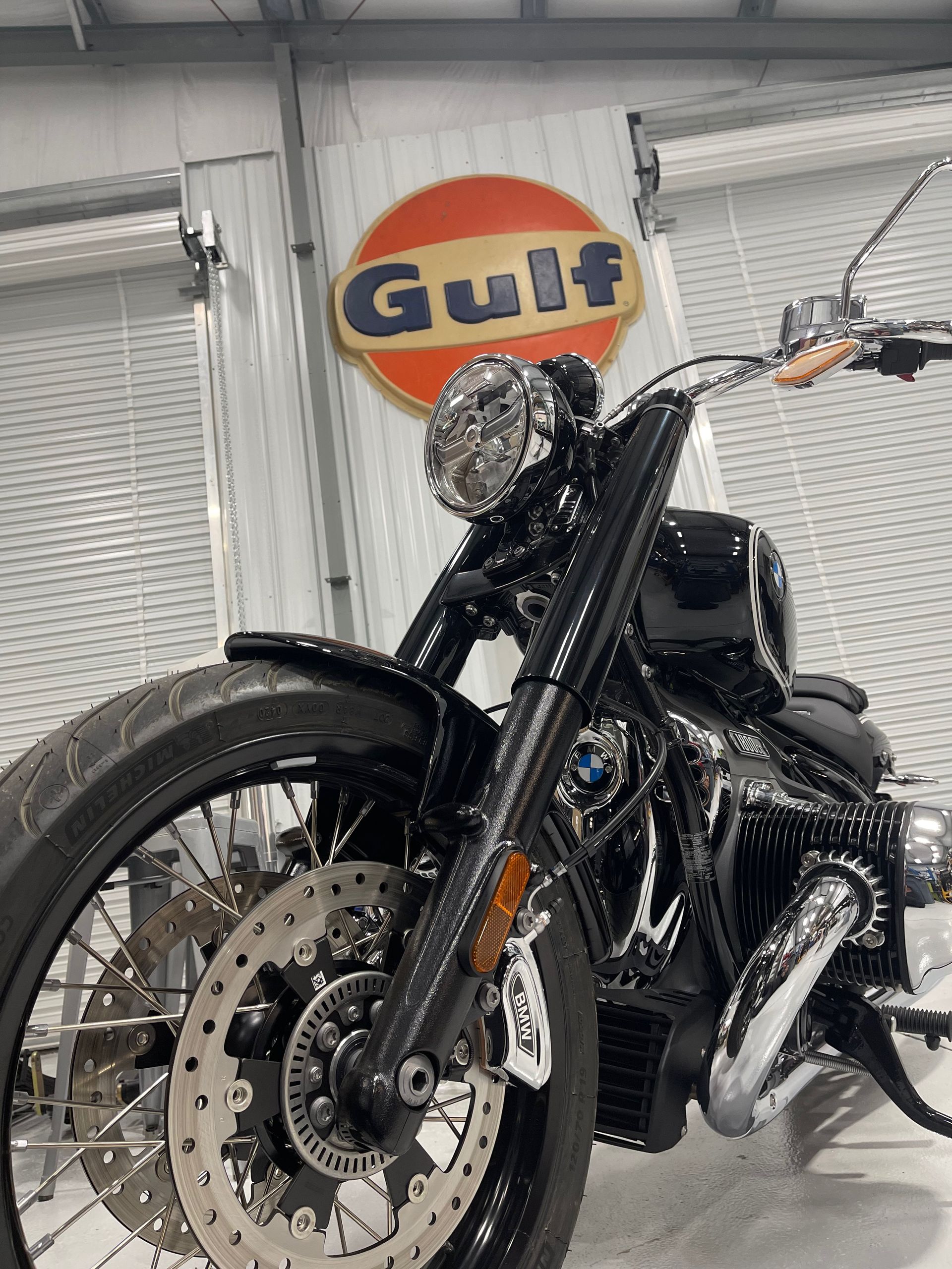 A motorcycle is parked in front of a gulf sign.