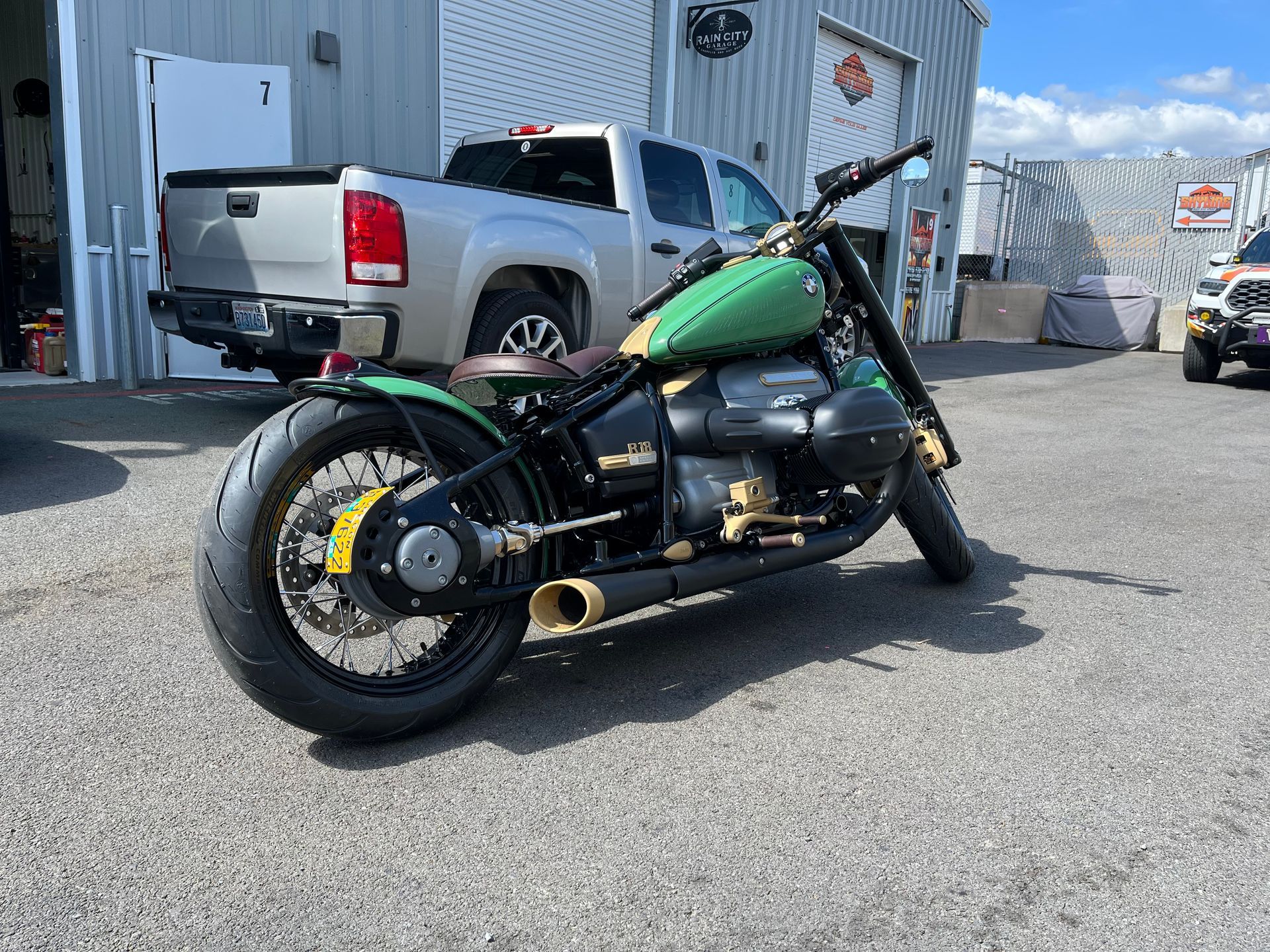 A green motorcycle is parked in a parking lot next to a truck.