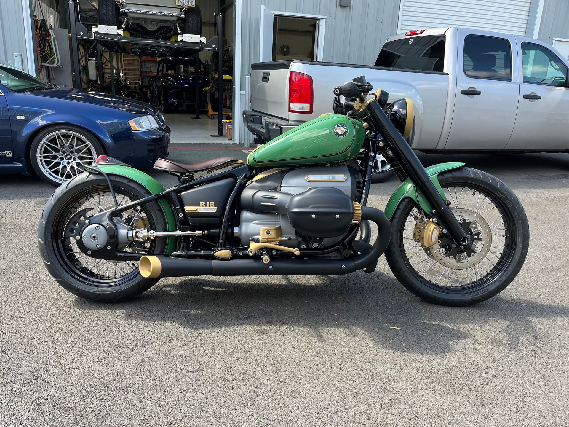 A green motorcycle is parked in a parking lot next to a truck.
